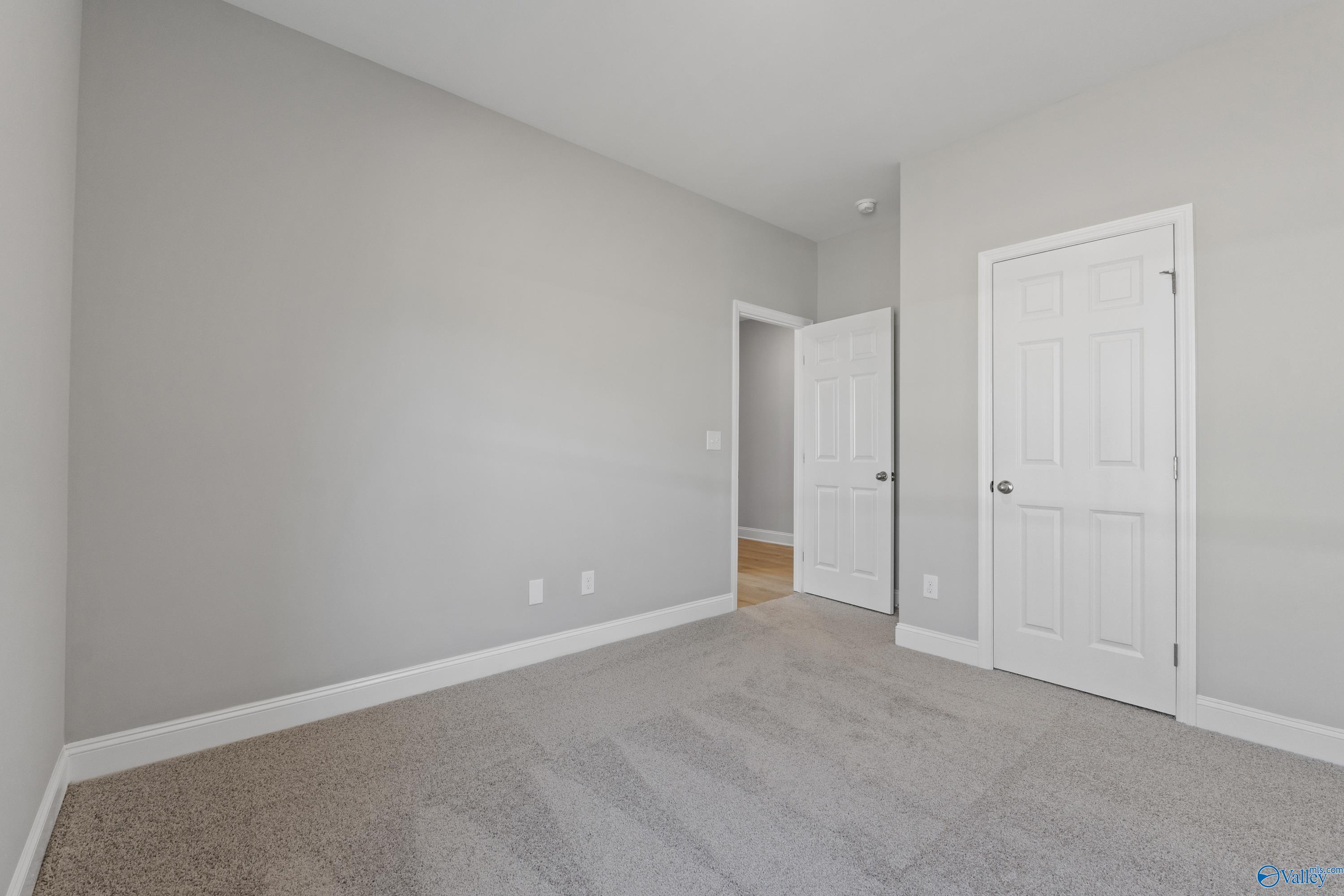 Bright secondary bedroom featuring gray walls, white doors, and carpeted floor in Davidson Homes The Asheville C, Athens, Alabama