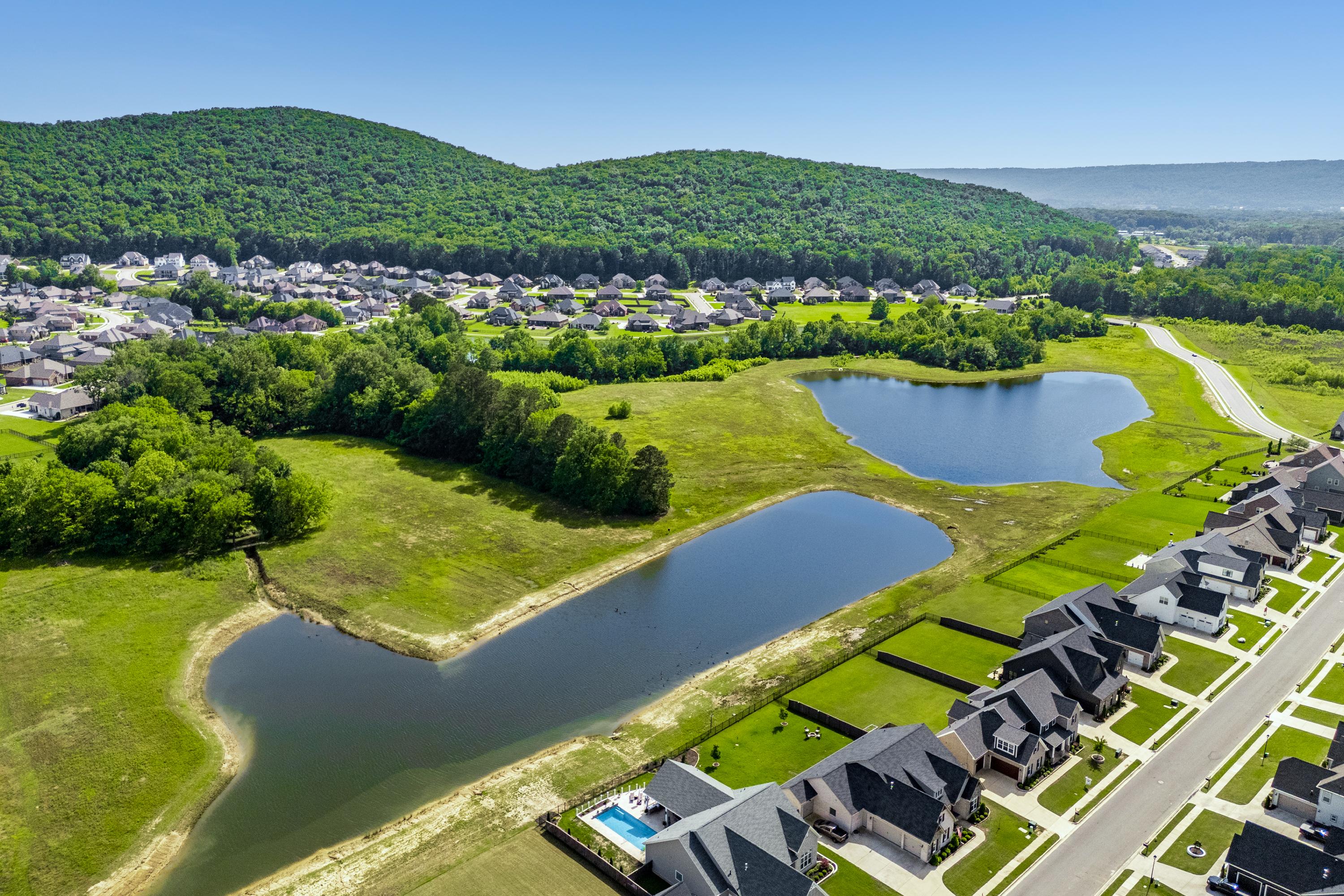 Aerial view of The Meadows at Hampton Cove in Owens Cross Roads Alabama with modern homes serene ponds and lush green hills