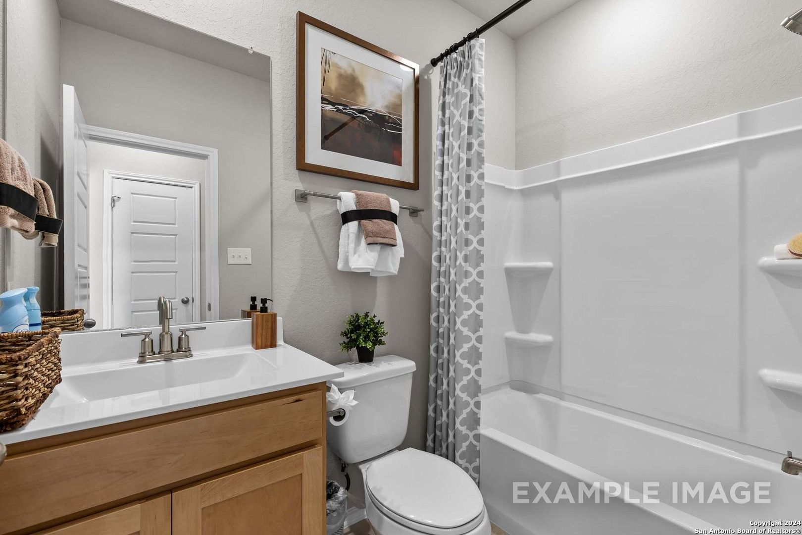 Elegant bathroom with white tub, glass shower, wooden vanity sink, and gray patterned curtain in Davidson Homes Sabine B, San Antonio