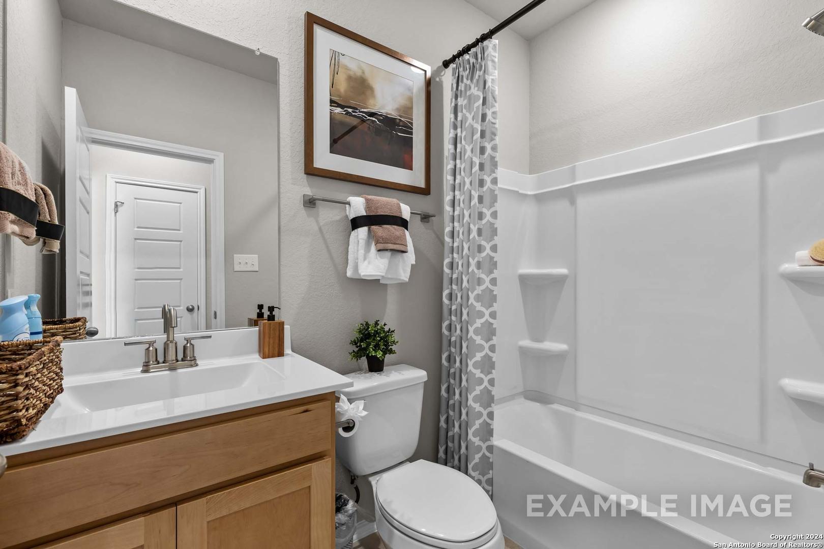 Elegant bathroom with white tub, glass shower, wooden vanity sink, and gray patterned curtain in Davidson Homes Sabine B, San Antonio