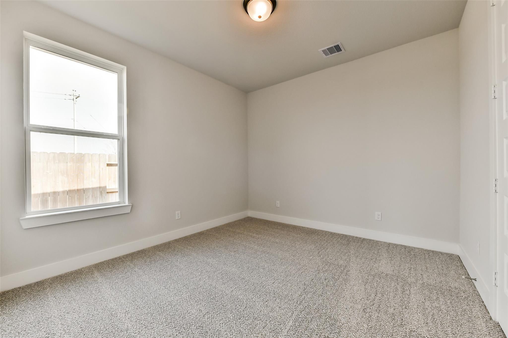 Bright secondary bedroom with beige carpet, white walls, and large window in Davidson Homes The George A, Lago Mar, Texas City, Texas