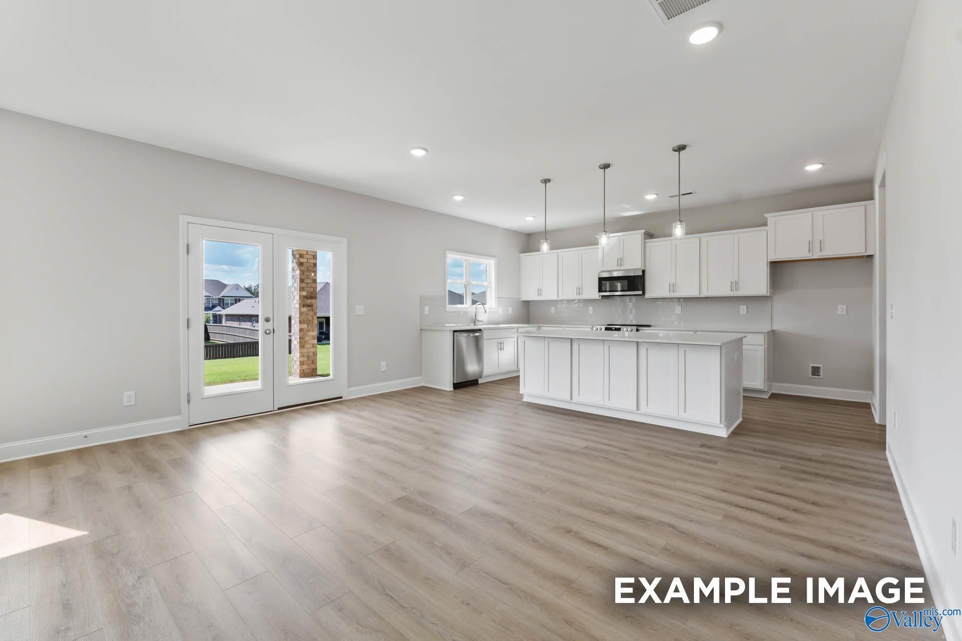 Modern open-concept kitchen with white cabinets, large island, stainless appliances, and French doors to backyard in Davidson Homes The Chelsea D, New Market, Alabama