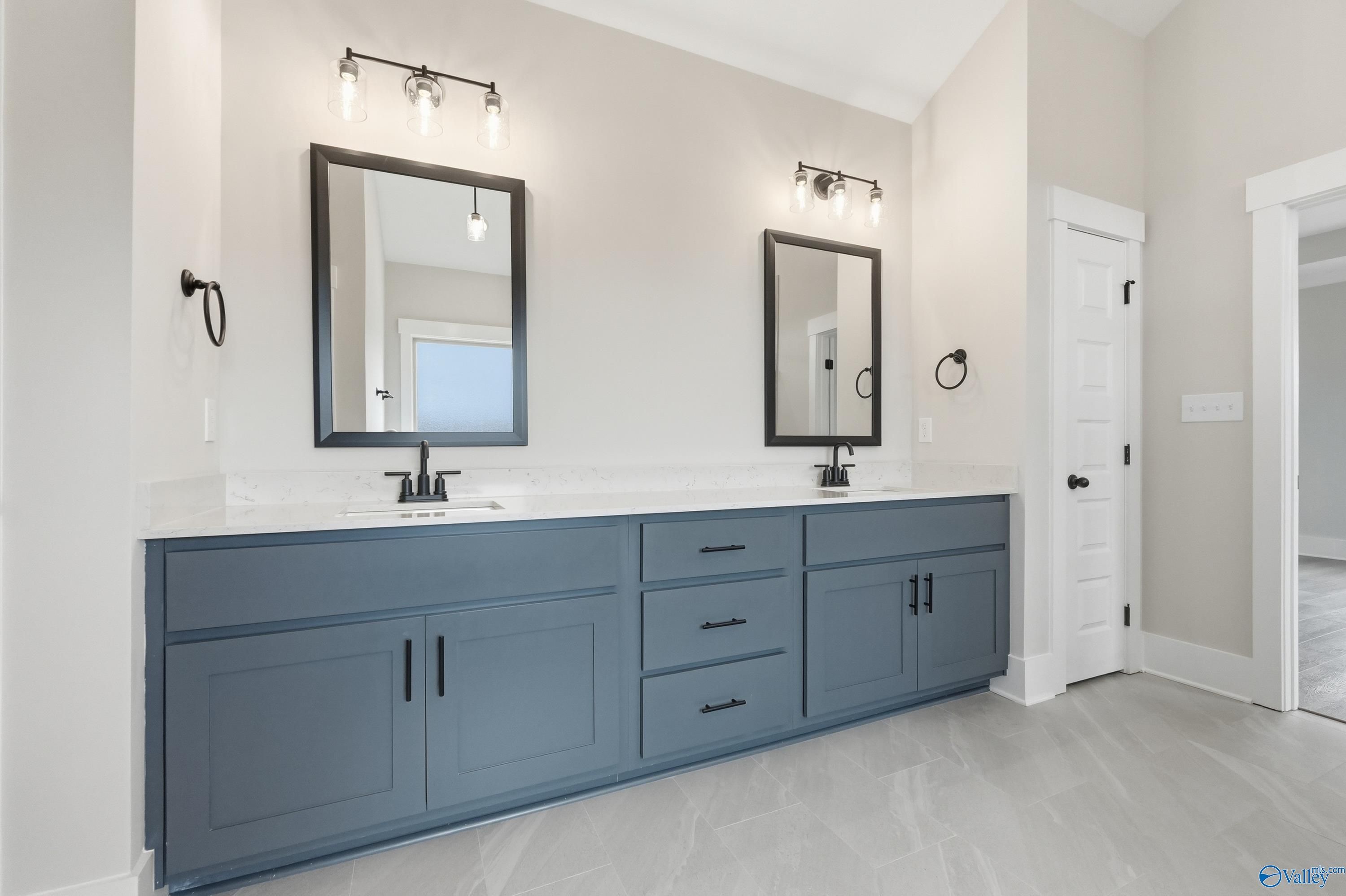 Modern master bathroom double vanity with navy cabinets, quartz counters, and framed mirrors in Davidson Homes The Finleigh, Meridianville AL