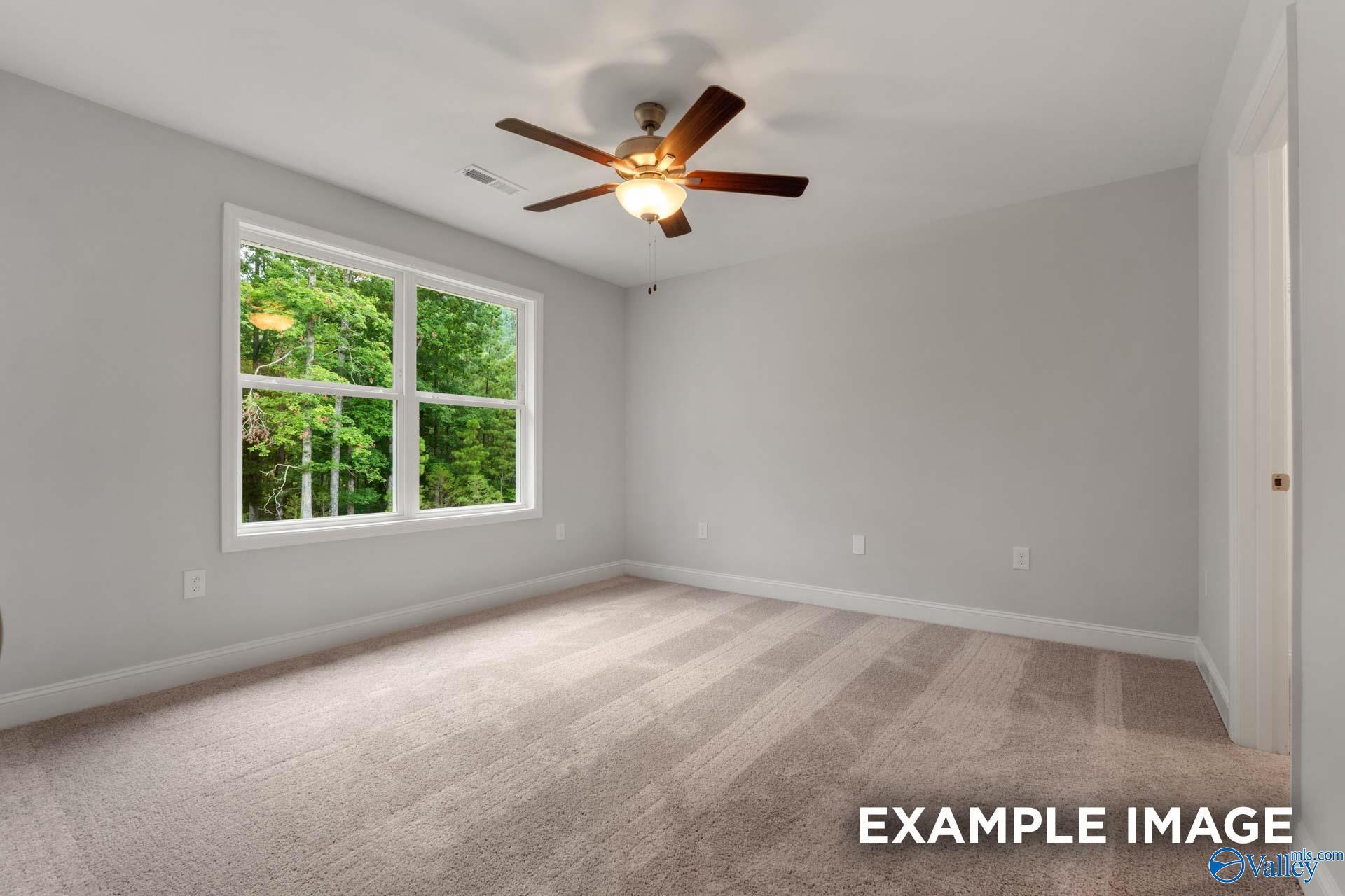 Bright secondary bedroom with large window to lush trees, ceiling fan, beige carpet in Davidson Homes The Shelby C, Arab, Alabama