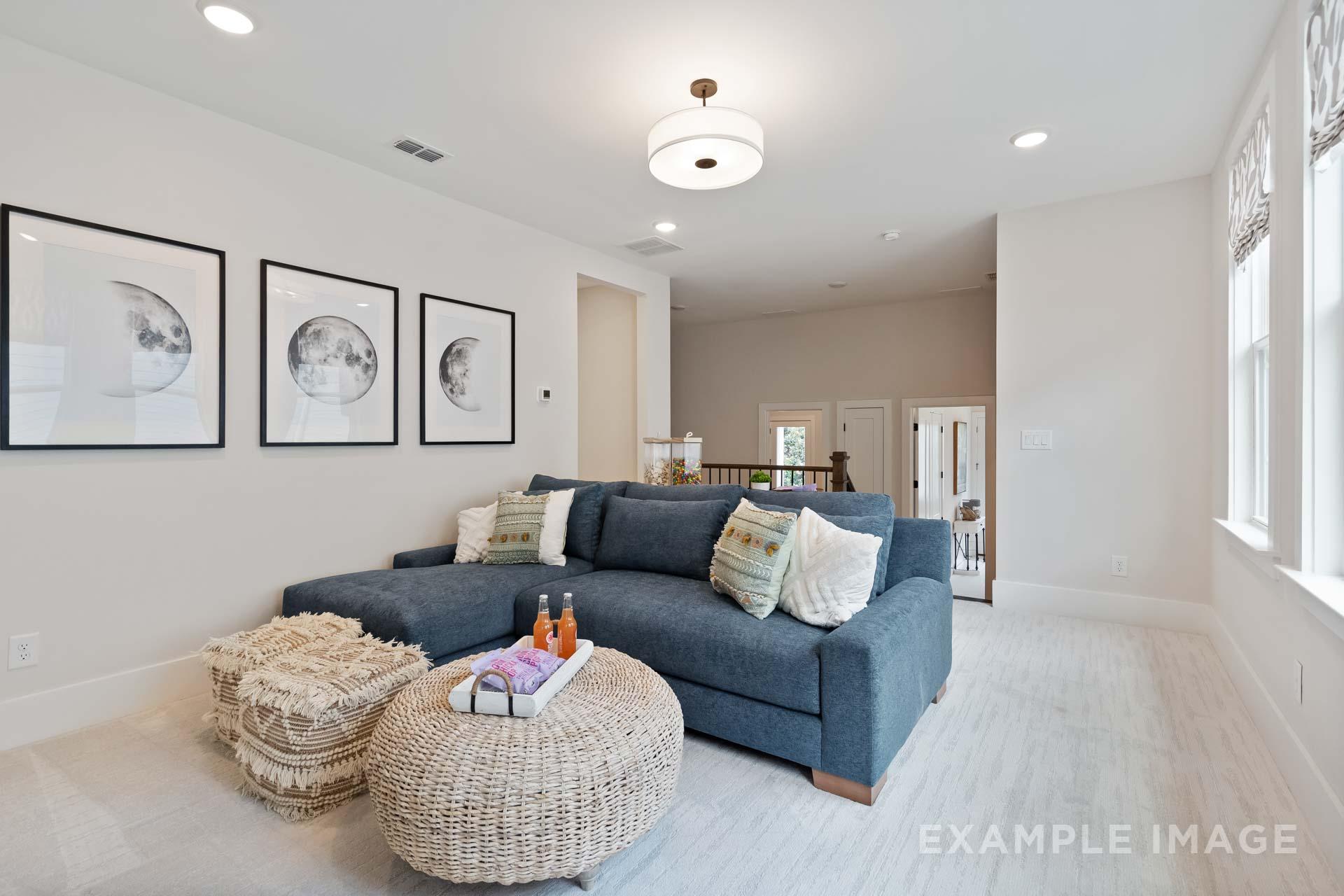 Spacious family room in Manor Estates Marietta GA with navy L-shaped sectional sofa, woven ottoman, moon wall art, and chandelier