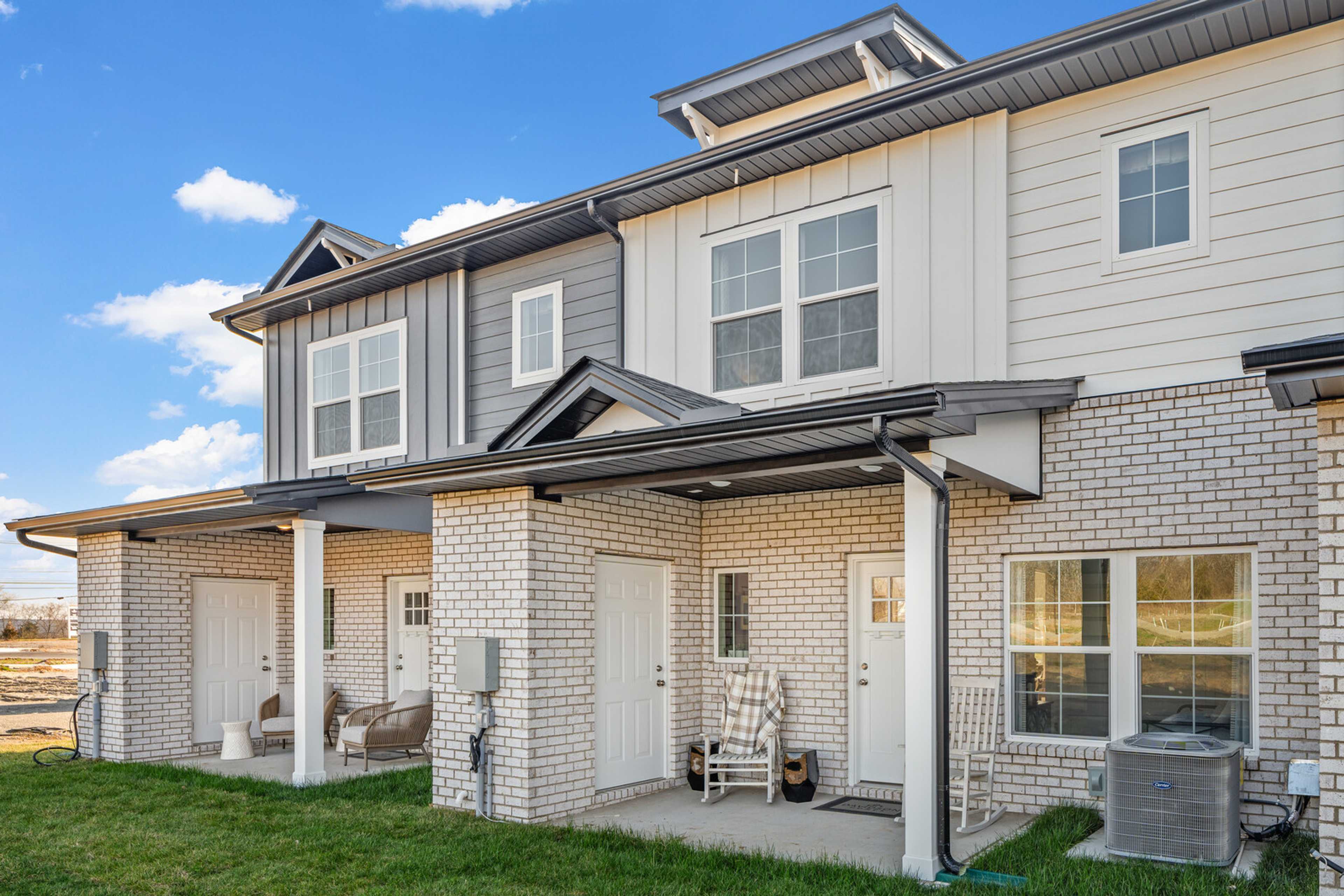 Charming townhome exteriors at The Towns at Red River in Gallatin TN with covered porches, brick siding, and rocking chairs
