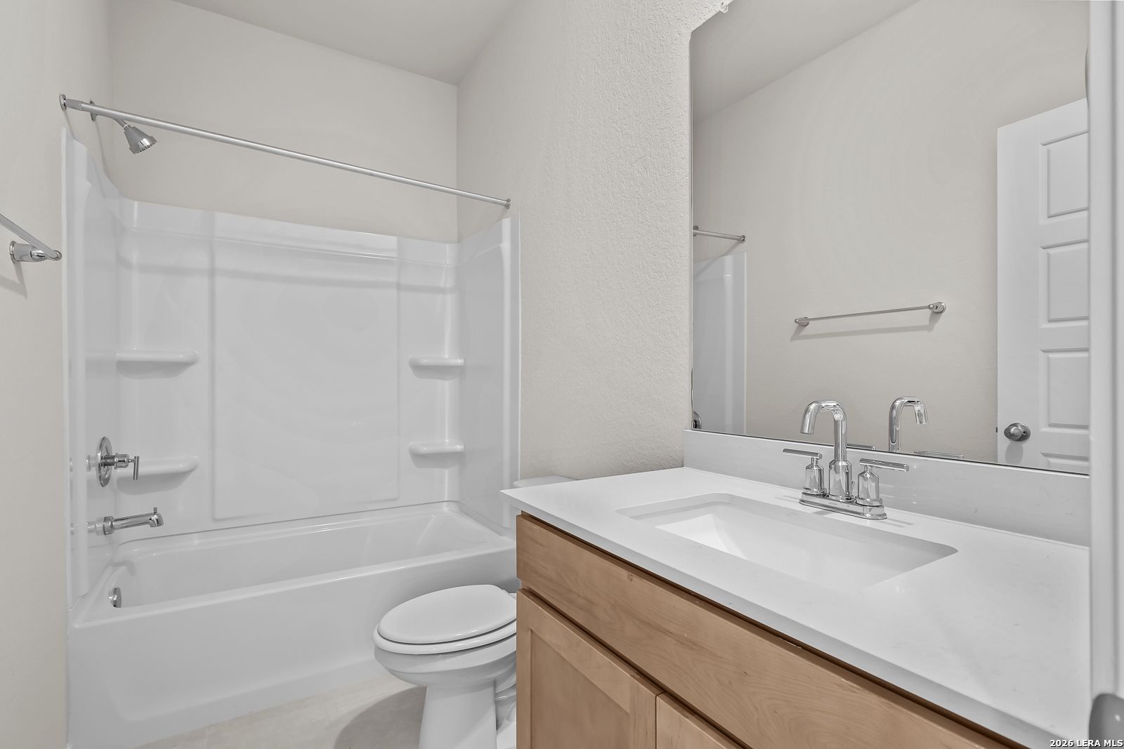 Modern bathroom with shower-tub combo and wood vanity in The Gillian B floor plan at Meadows at Oak Creek, San Antonio.
