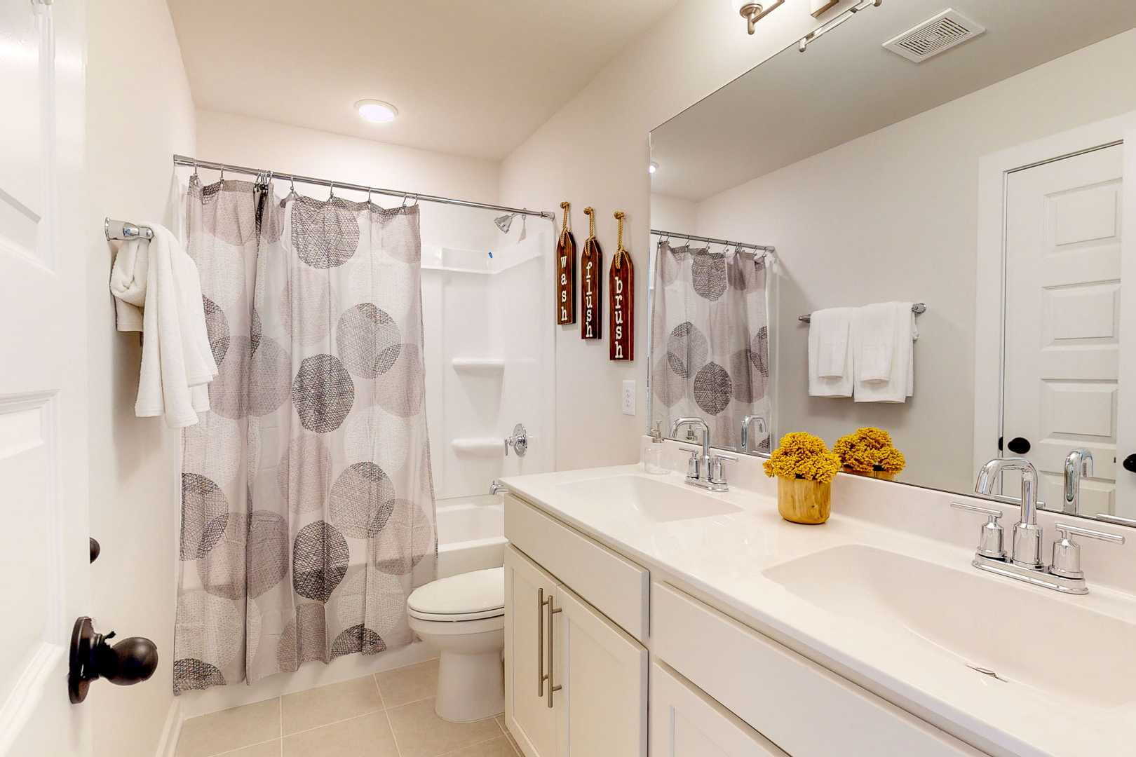 Modern bathroom at Liberty Creek in Gallatin TN with double vanity, polka dot shower curtain, toilet, and yellow flowers