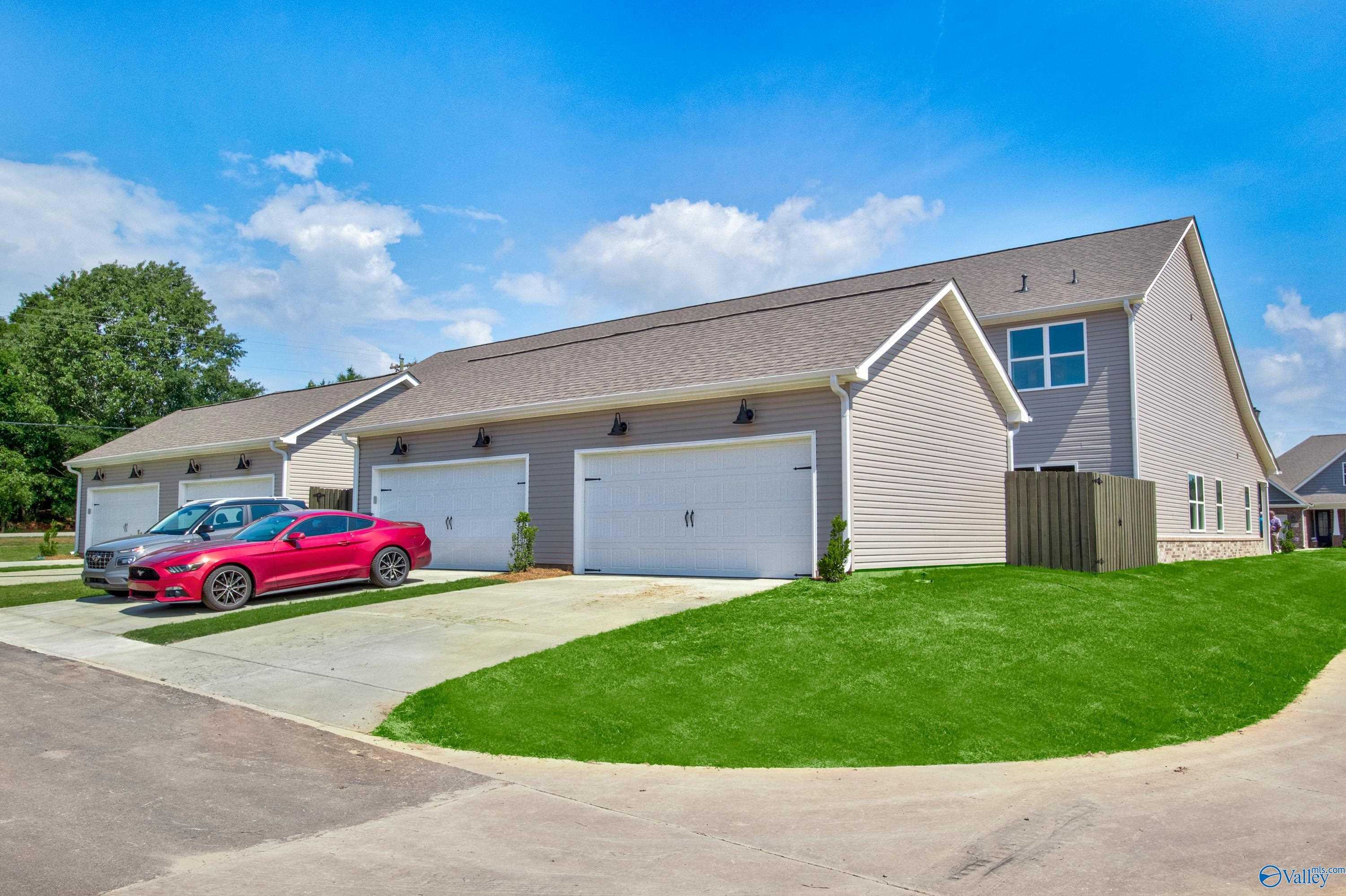 Modern 2-story home exterior with 2-car garage, red sports car in driveway, lush green yard in River Road Estates, Decatur, Alabama