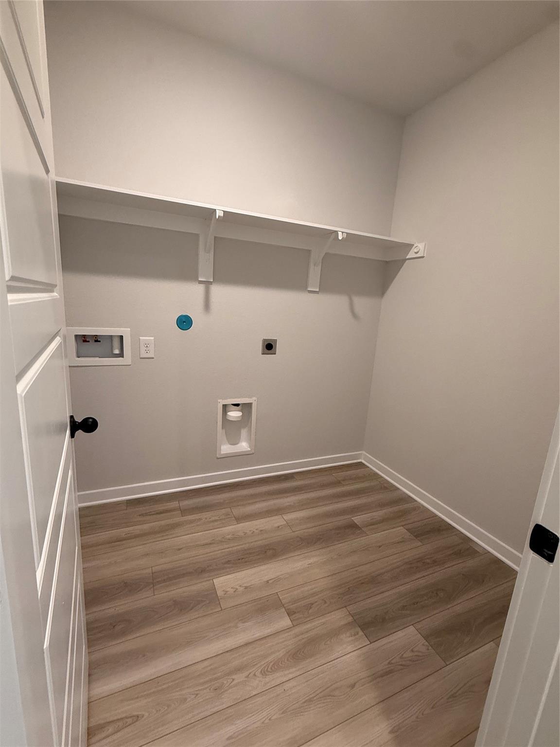 Dedicated laundry room with wood-look flooring and shelving in The Sorrento E floor plan at Sundance Cove, Crosby, Texas.