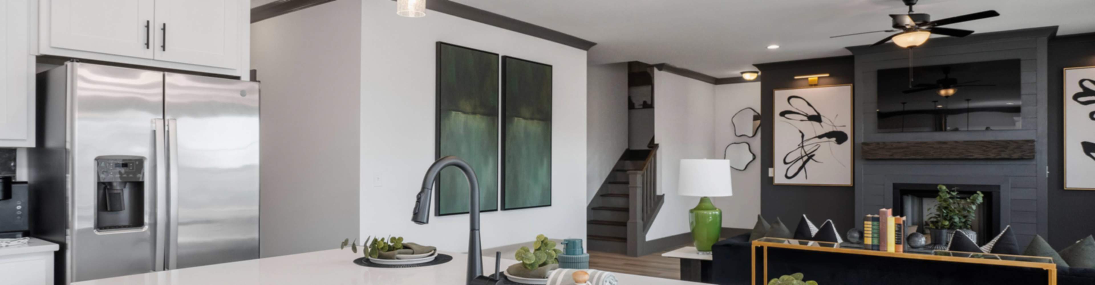 Modern white kitchen island with stainless sink, fridge, and pendant lights in new Josephine home