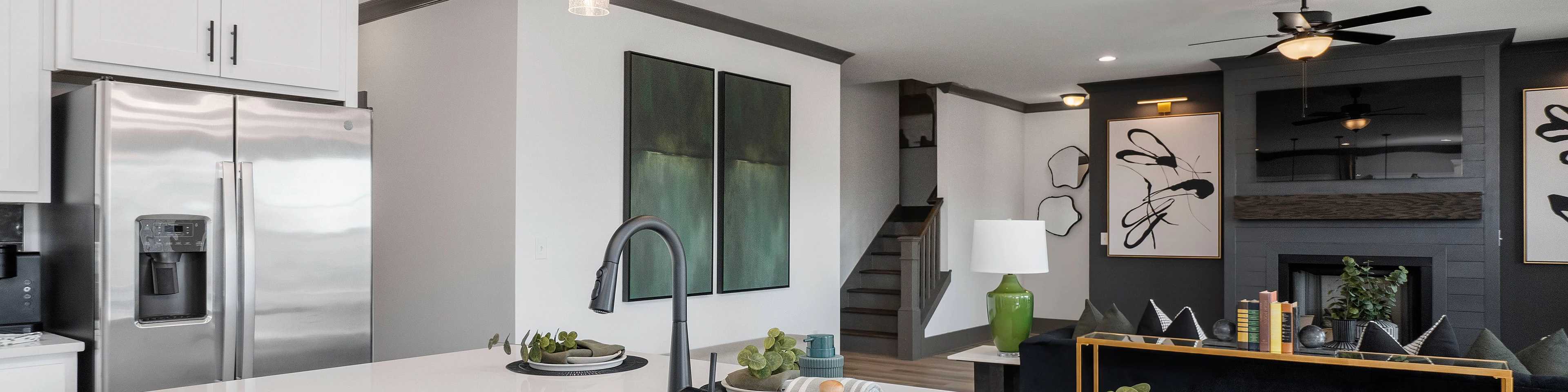 Modern white kitchen island with stainless sink, fridge, and pendant lights in new Josephine home
