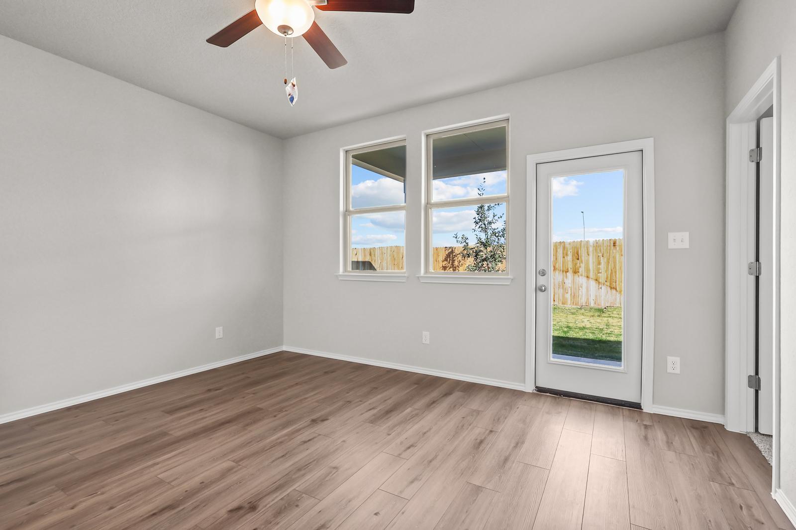 Bright master bedroom in The Arroyo featuring wood-look flooring, ceiling fan, and patio access in San Antonio, Texas.