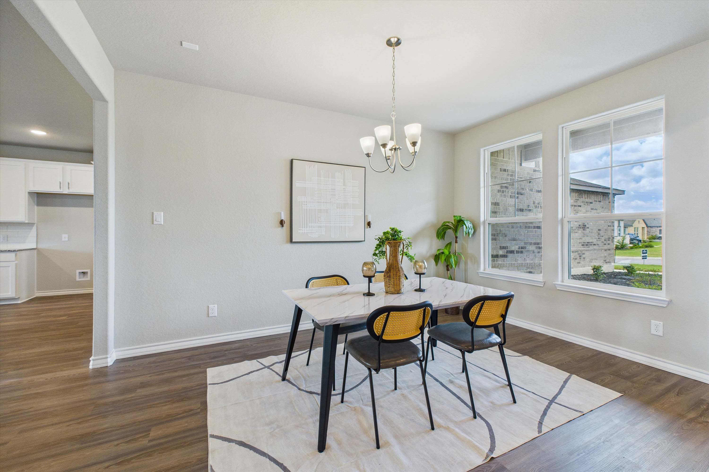 Bright dining area in The Foster E home design featuring a marble-top table, modern chairs, and open-concept layout.