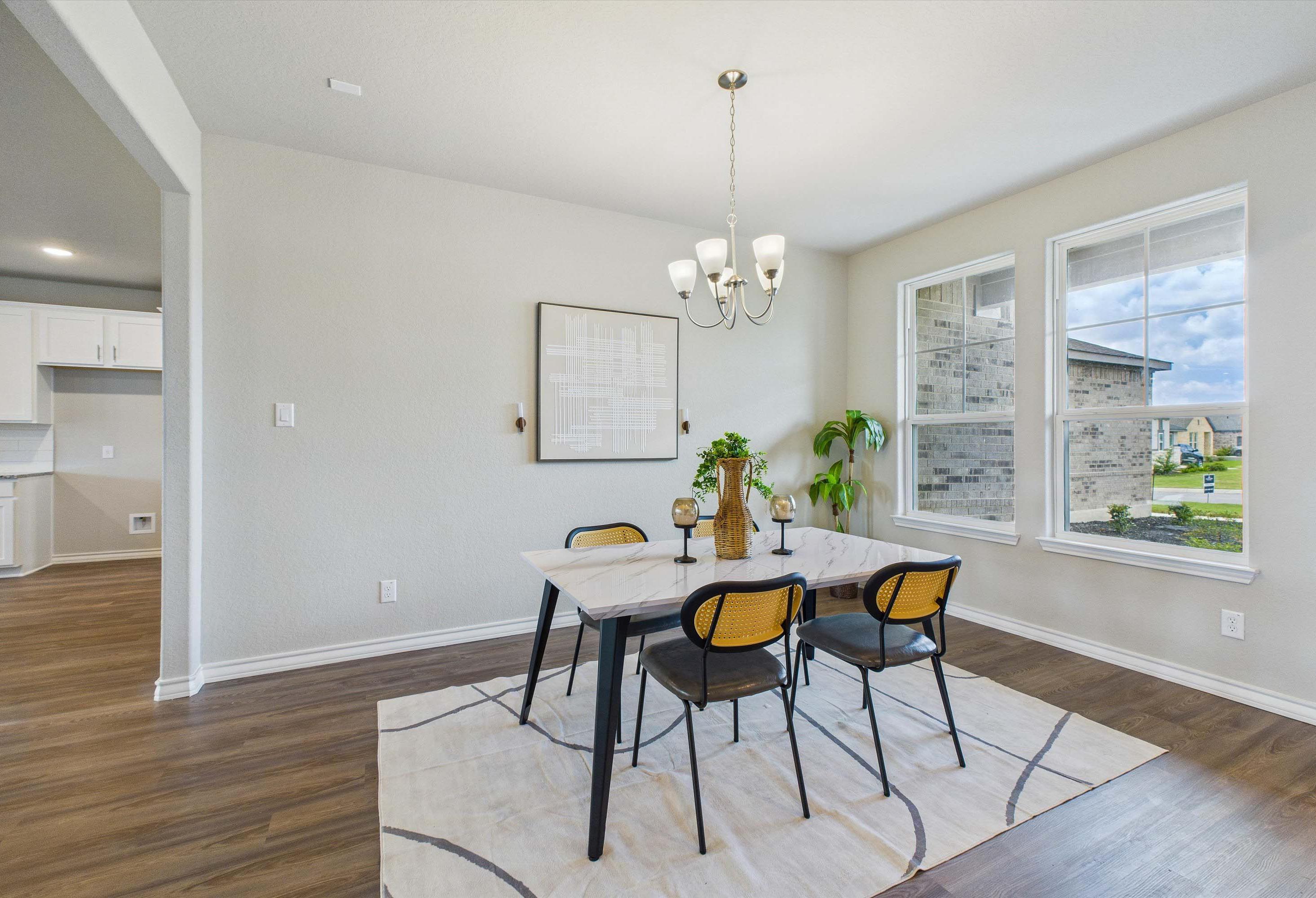 Bright dining area in The Foster E home design featuring a marble-top table, modern chairs, and open-concept layout.