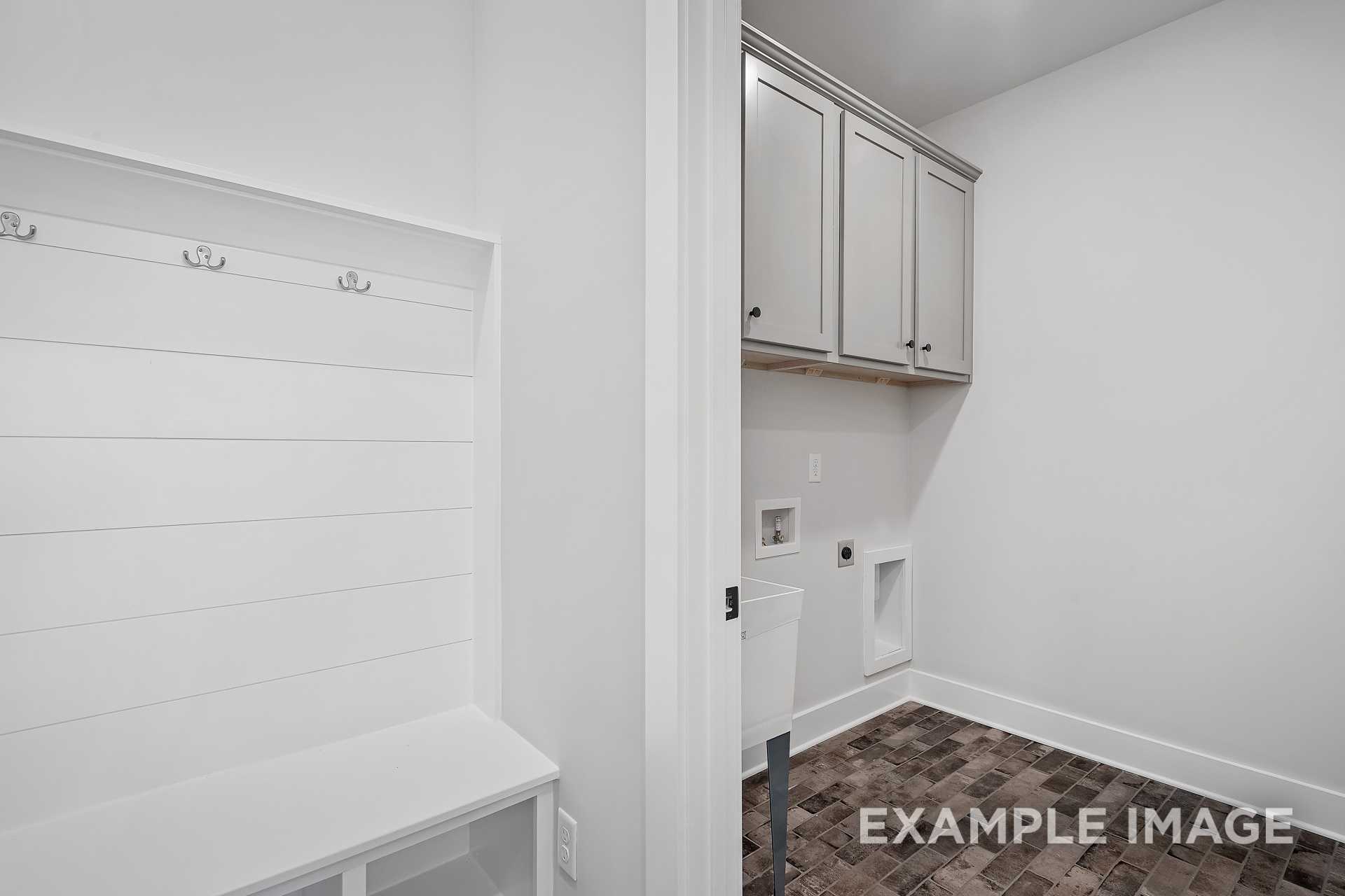 Mudroom and laundry in The Hathaway home by Davidson Homes featuring shiplap walls, built-in bench, hooks, and utility sink