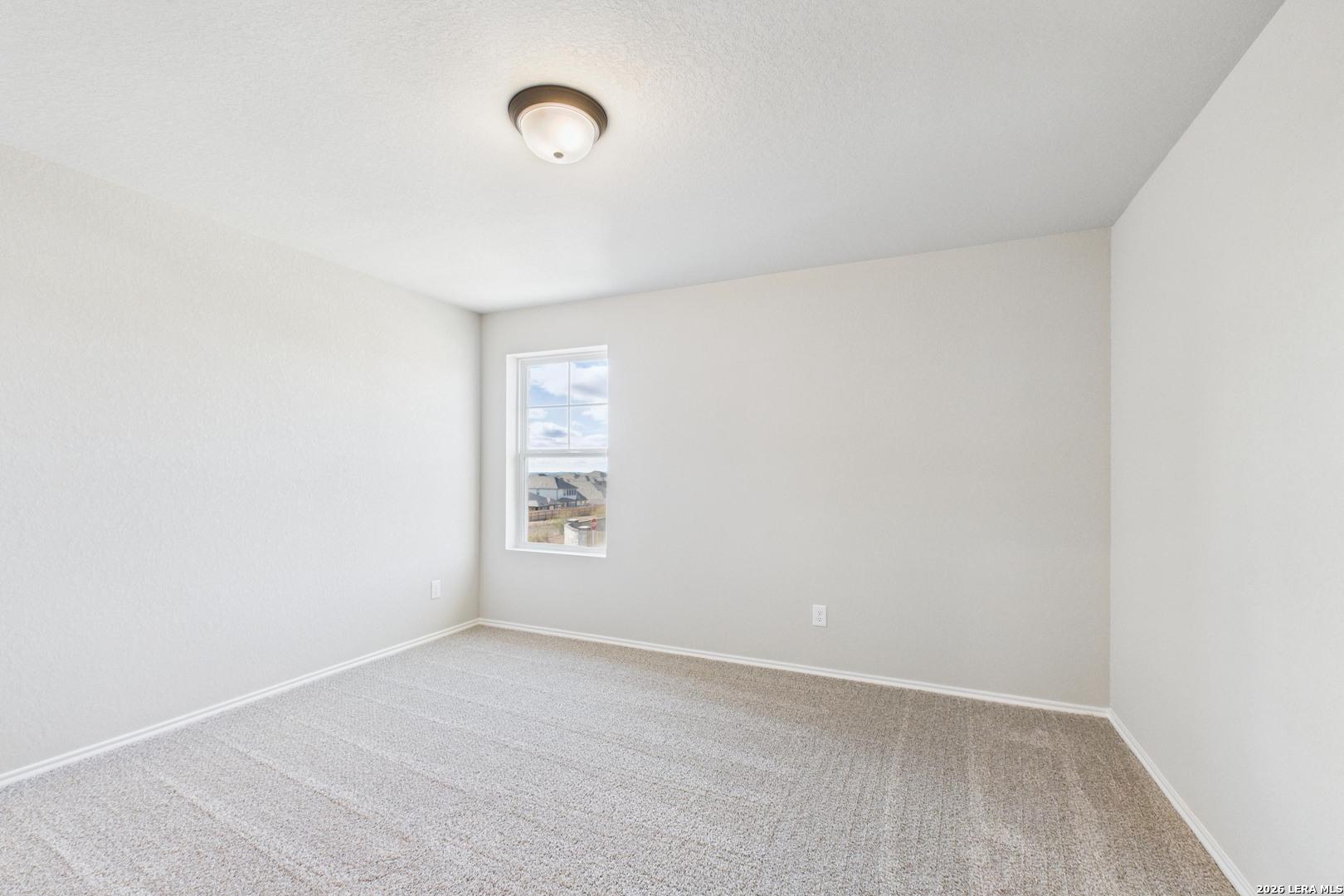 Bright secondary bedroom with neutral walls, beige carpet, and large window in Davidson Homes Douglas E, Bricewood, San Antonio