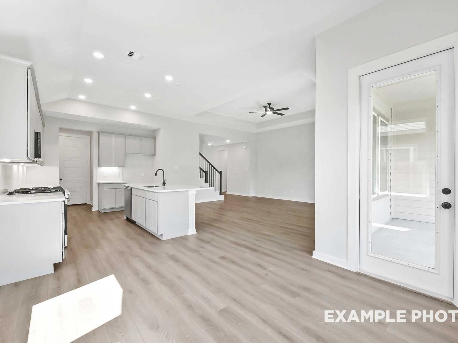 Open-concept kitchen and living area with light wood floors in The Sequoia C floor plan by Davidson Homes in Crosby, TX.