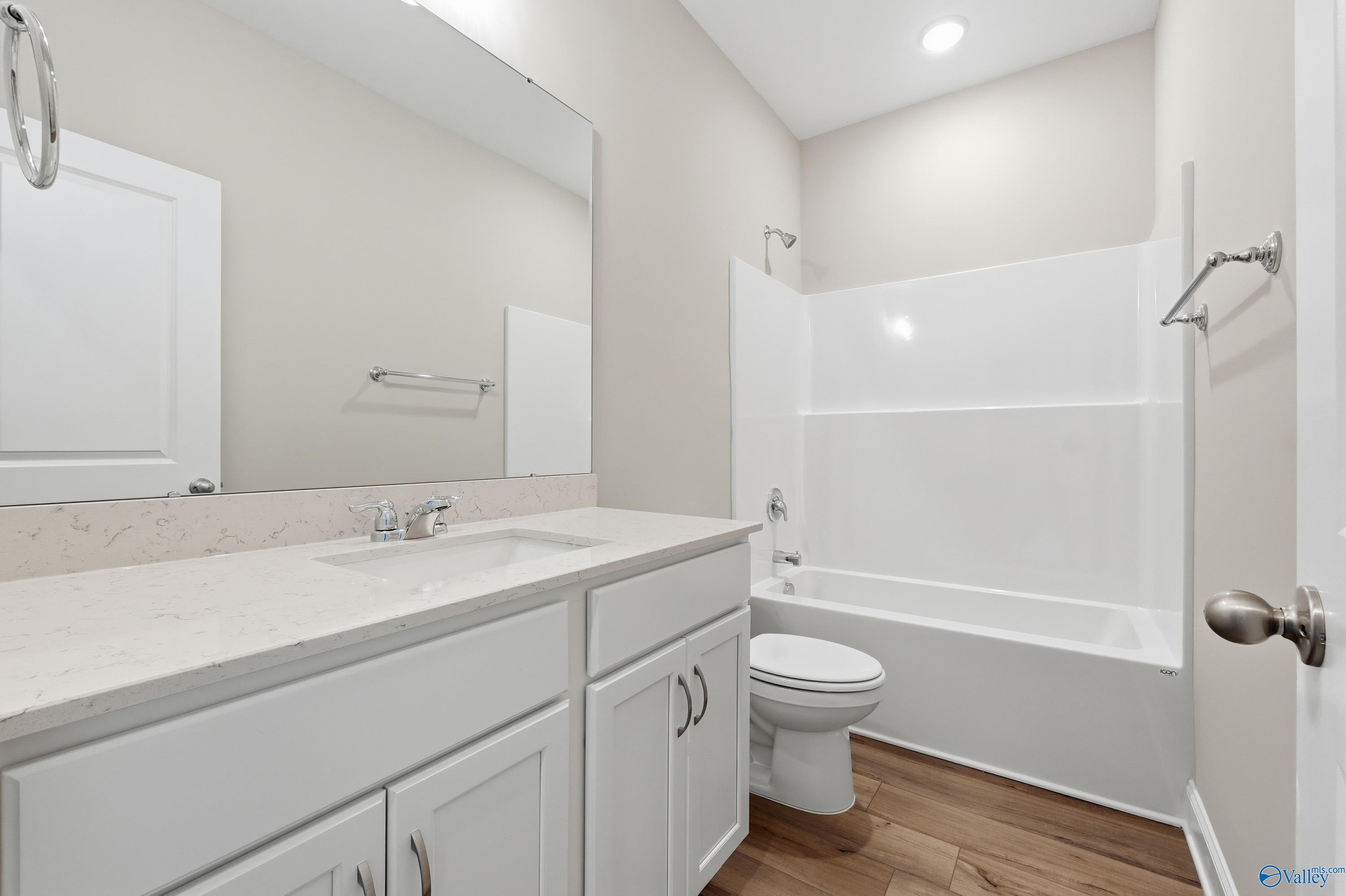 Modern secondary bathroom with quartz double vanity, tub-shower combo, and hardwood floors in Davidson Homes The Asheville, Arab, AL