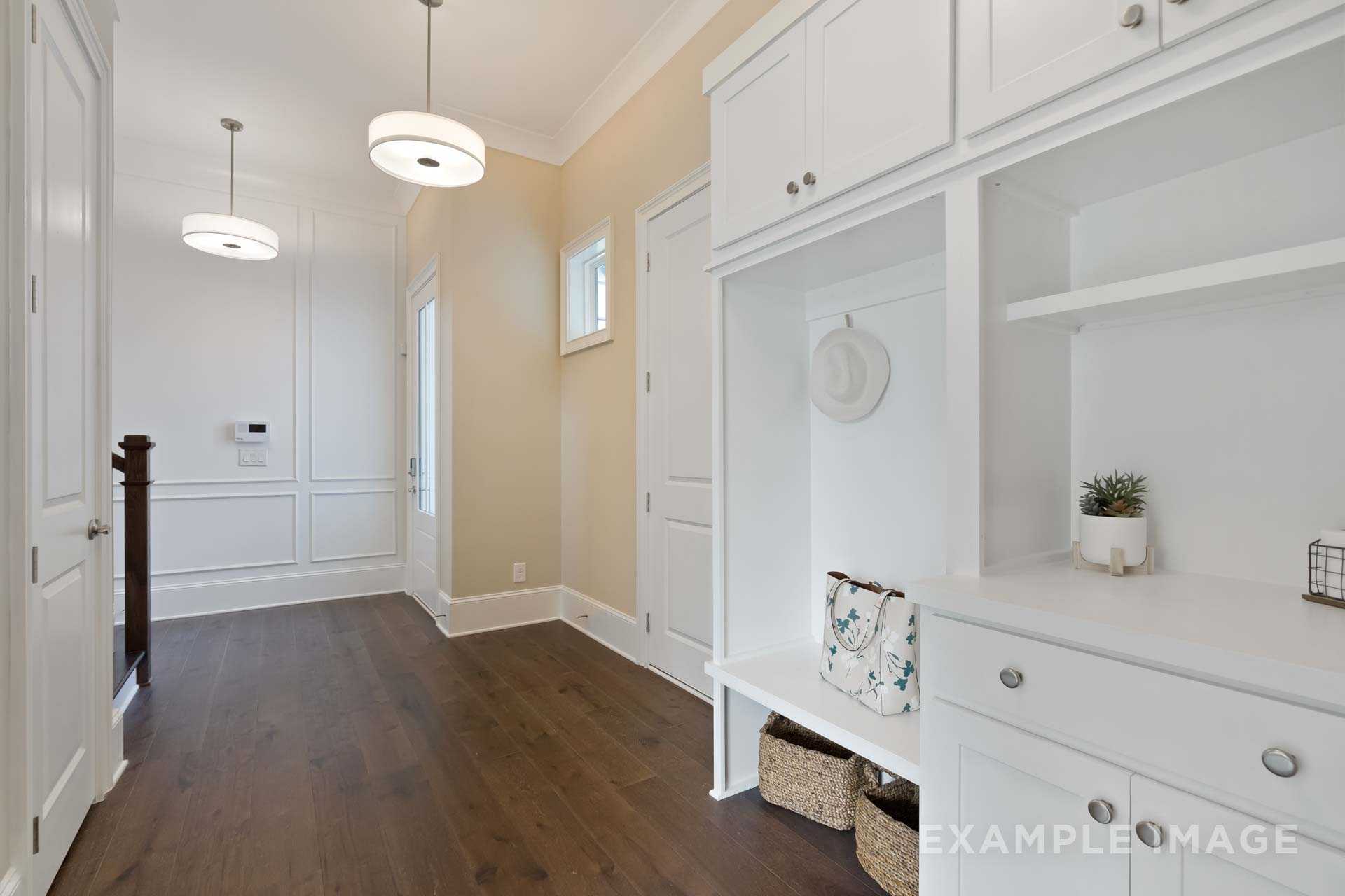 Spacious mudroom in The Seaside B by Davidson Homes featuring white cabinetry, built-in bench, open shelving, and hardwood floors