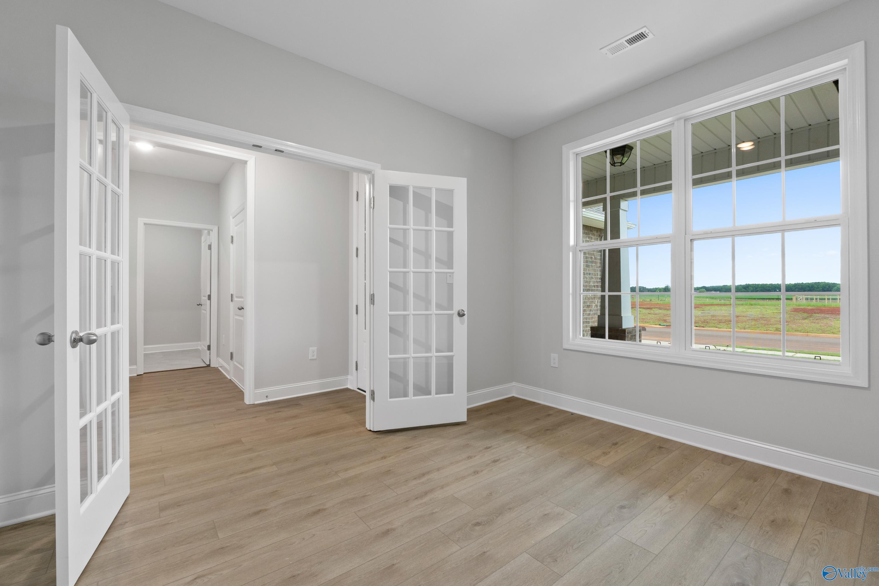 Spacious bonus room with open French doors, hardwood floors, and large windows overlooking fields in Davidson Homes The Rockford B, Toney, Alabama