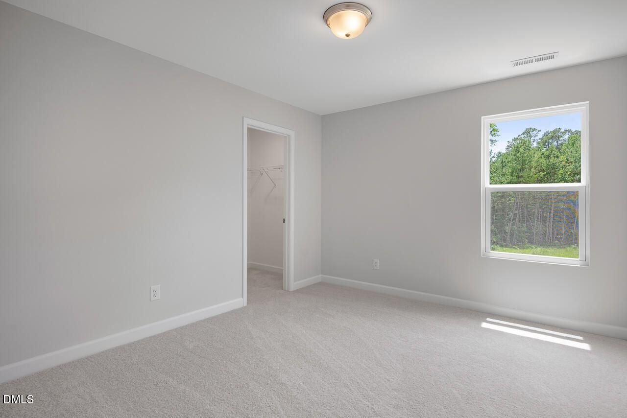 Bright secondary bedroom with walk-in closet in The Hickory II B floor plan at Wellers Knoll, Lillington, North Carolina.