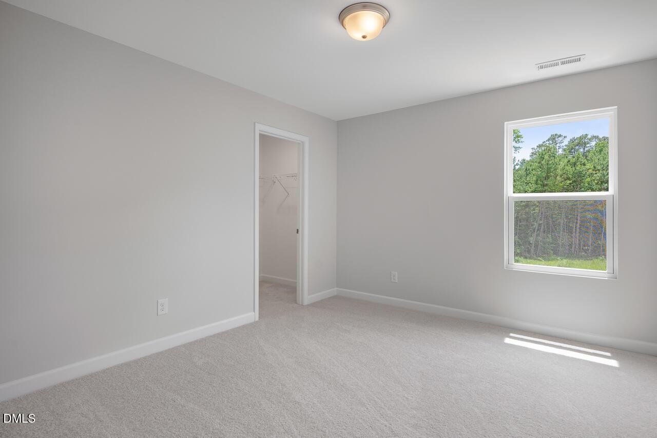 Bright secondary bedroom with walk-in closet in The Hickory II B floor plan at Wellers Knoll, Lillington, North Carolina.
