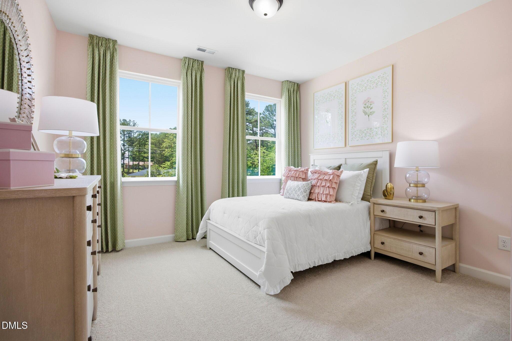 Bright, pink-walled secondary bedroom with white bedding in The Ashport M floor plan at Wendell Ridge, North Carolina.
