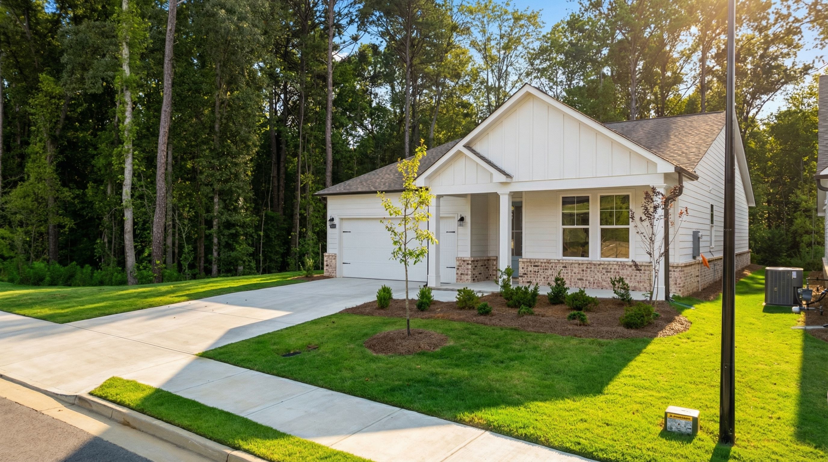 Modern white single-story 4-bedroom home with 2-car garage, front porch, and wooded yard in Kelly Preserve, Loganville, Georgia