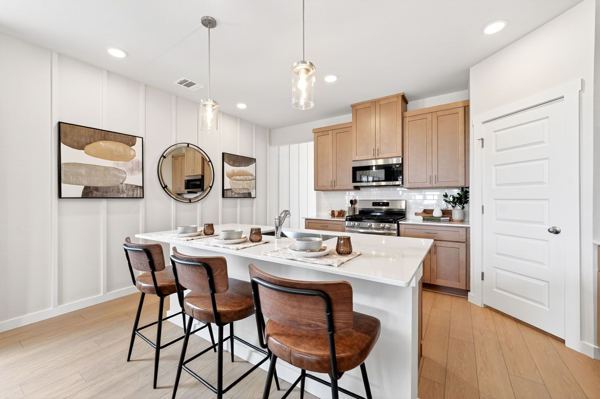Modern kitchen island at Heartland Texas with oak cabinets, white quartz counters, leather bar stools, and pendant lights