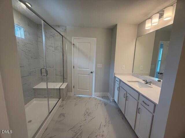 Modern master bathroom with frameless glass shower, marble tiles, and white vanity in Davidson Homes The Preston C, Lillington, NC