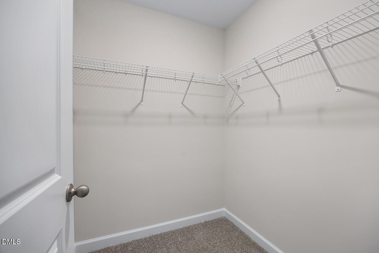 Spacious walk-in closet with white wire shelving and hanging rods in Davidson Homes The Grace C, Lillington, NC