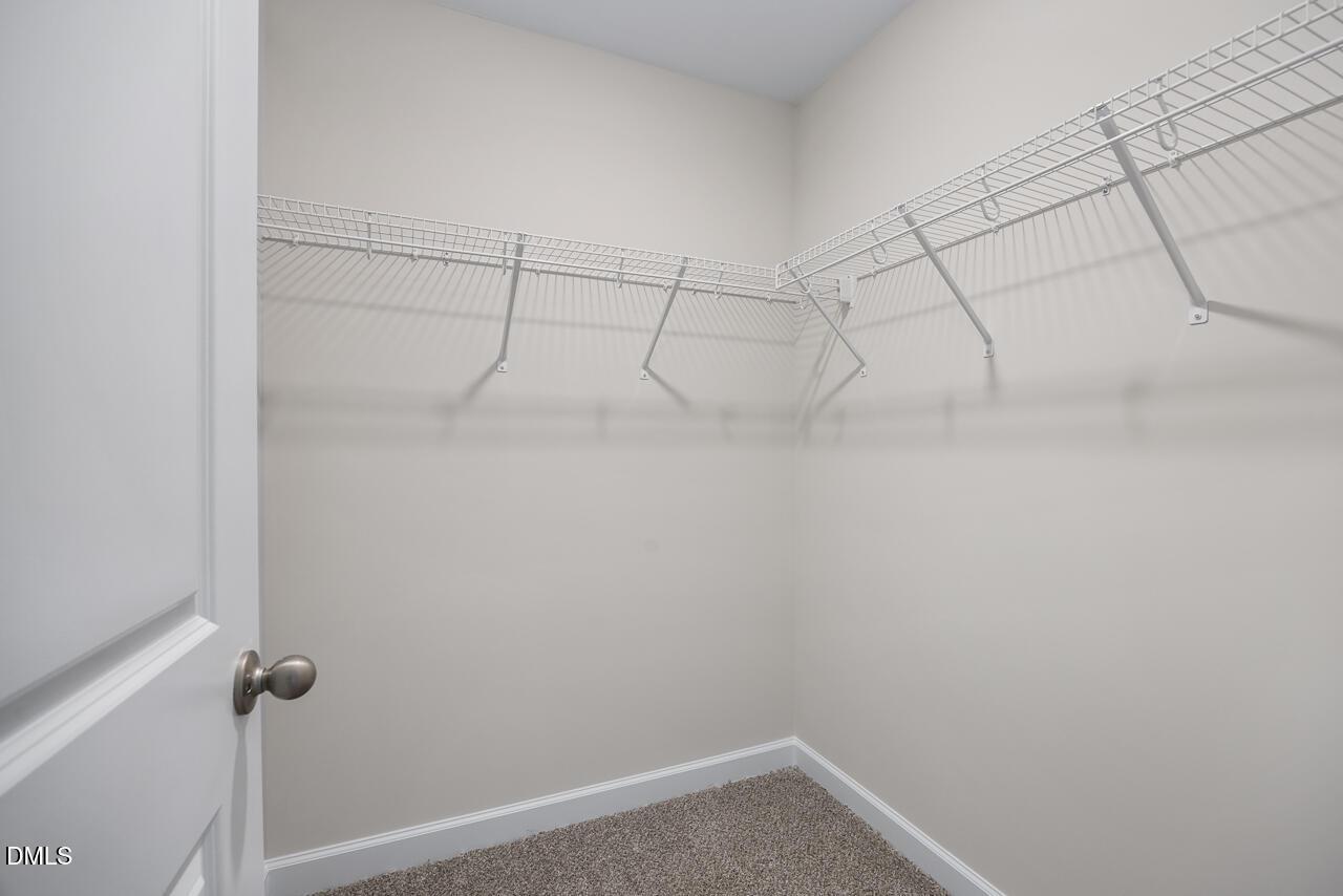 Spacious walk-in closet with white wire shelving and hanging rods in Davidson Homes The Grace C, Lillington, NC