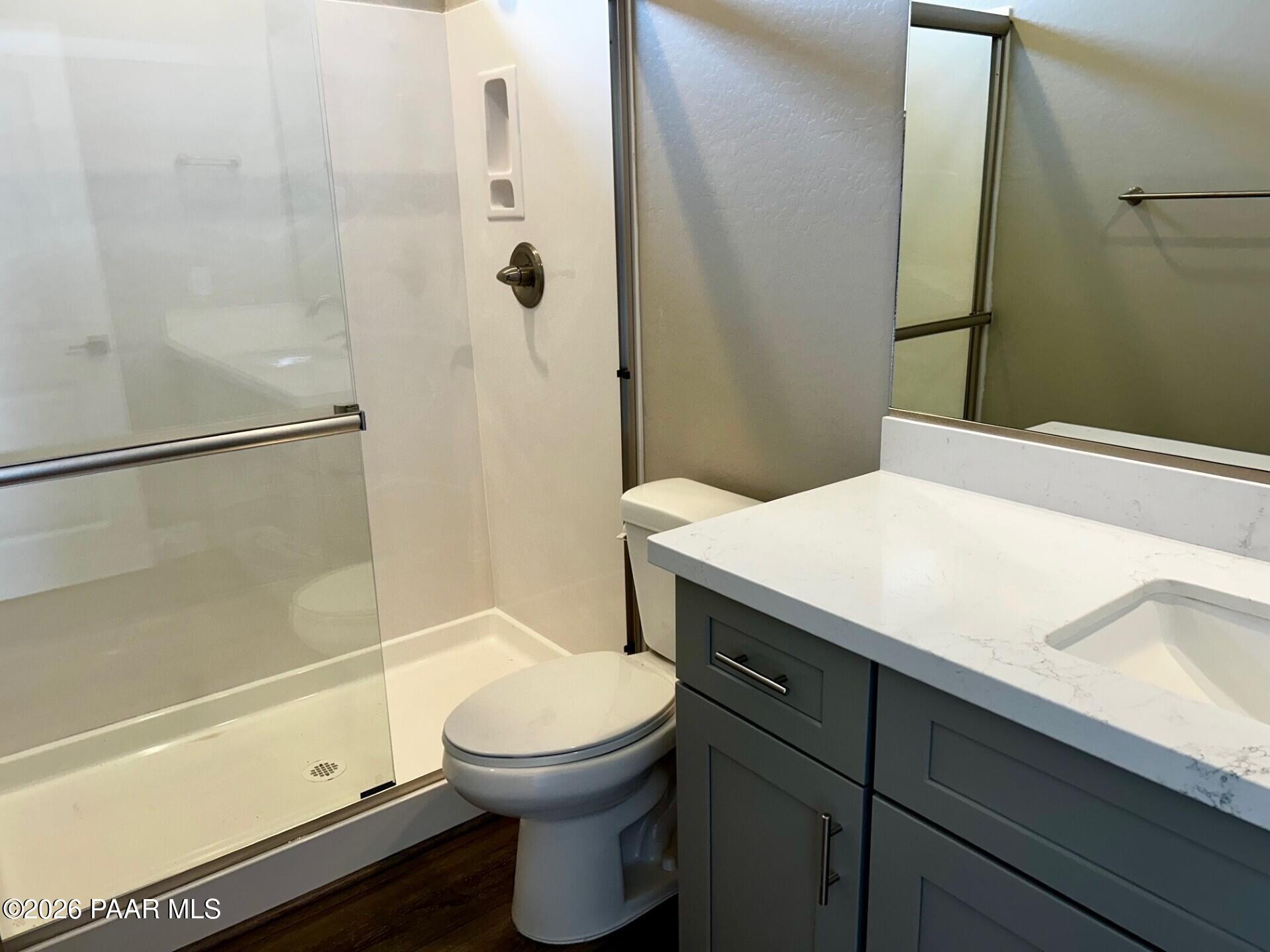 Modern bathroom featuring frameless glass shower, white tile, gray vanity, quartz countertop in Davidson Homes Harmony C, Prescott Valley AZ