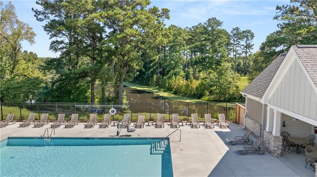 Resort-style community pool with lounge chairs overlooking scenic lake at Lake Shore by Davidson Homes in Winder, Georgia