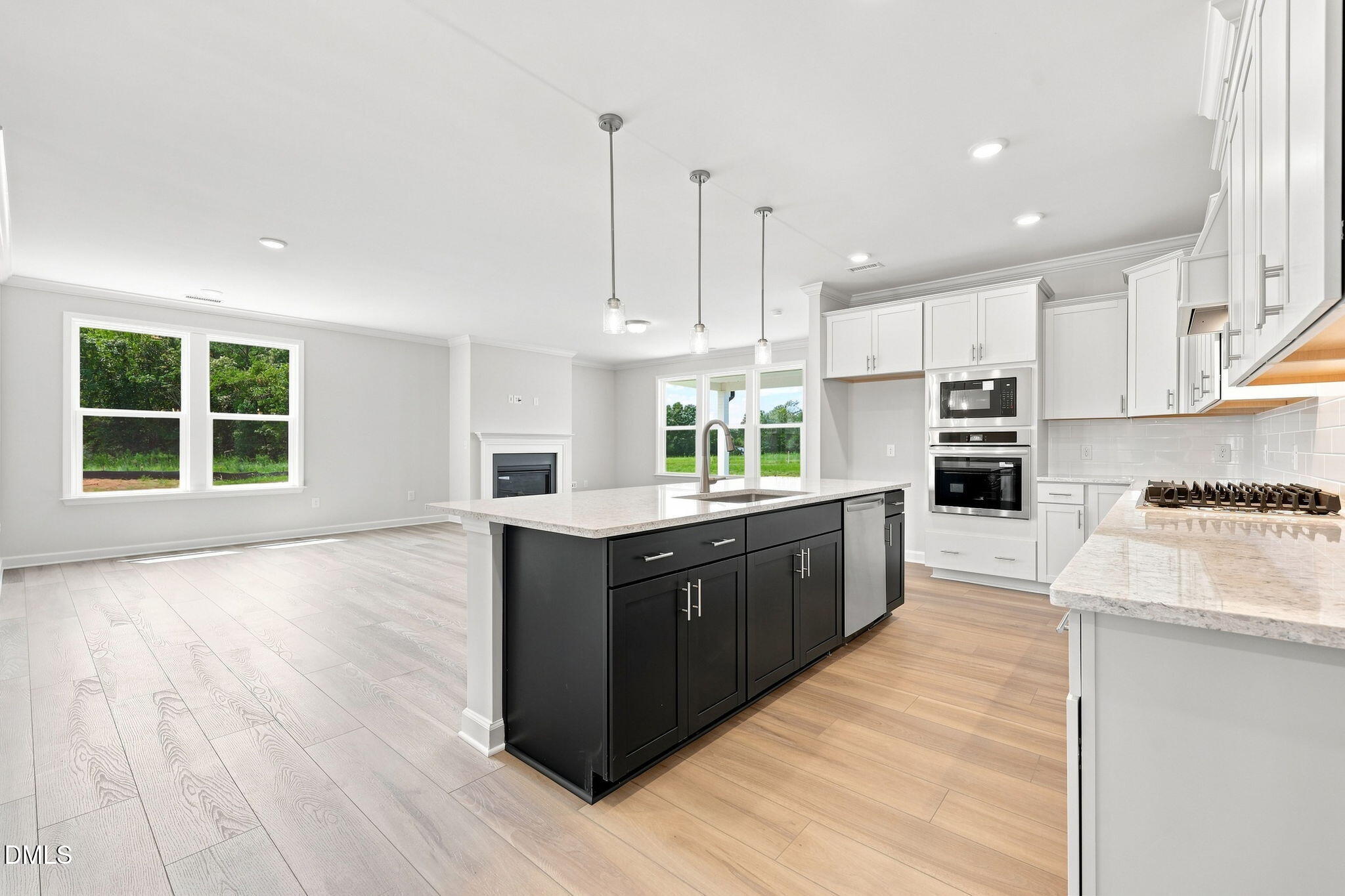 Open-concept kitchen with dark island and white cabinets in The Magnolia B floor plan at Retreat at North Main, Lillington.