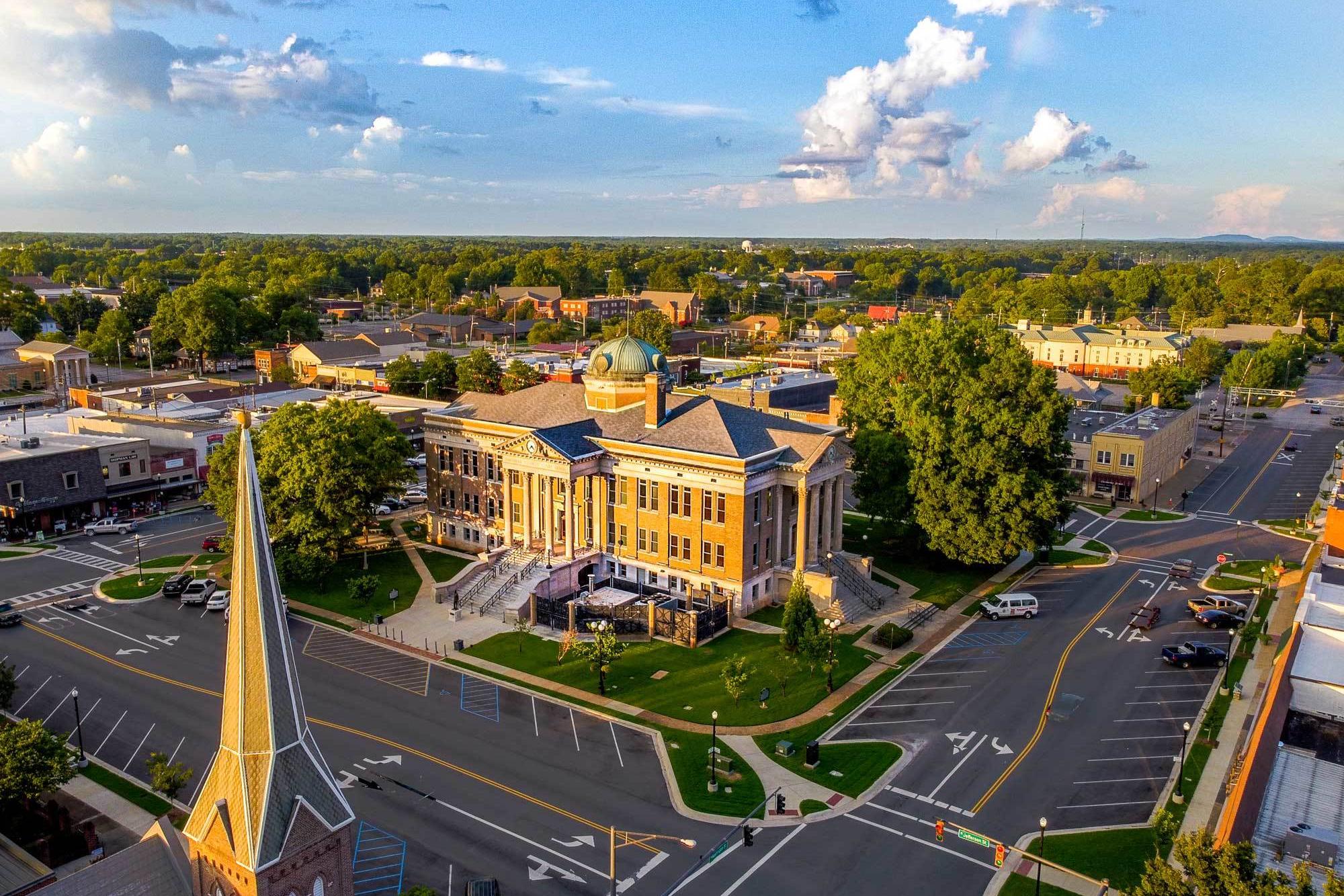 Aerial view of historic Athens Alabama courthouse with green dome, columns, trees, and downtown streets