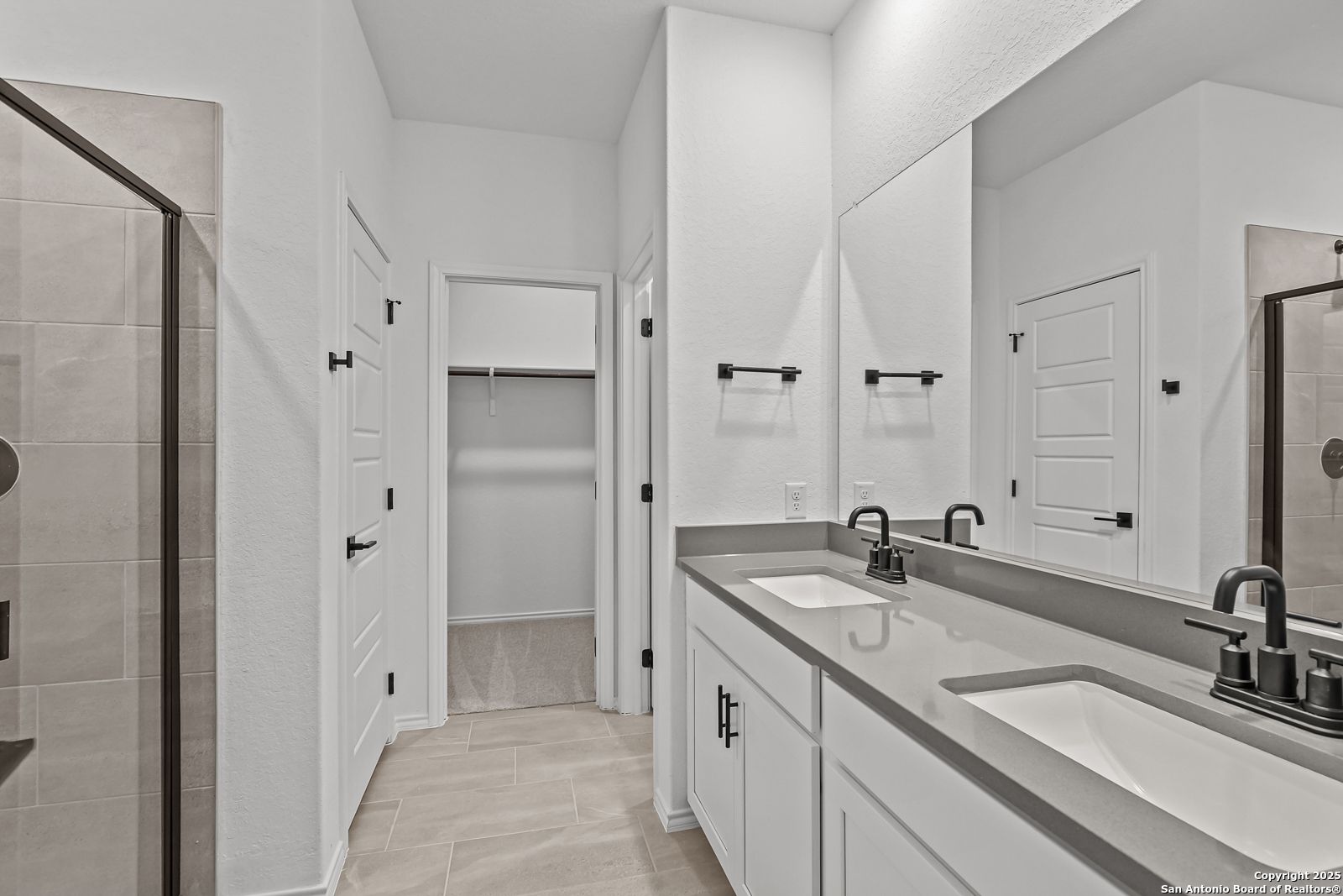 Modern master bathroom with double vanity, quartz counters, frameless glass shower in Davidson Homes The Daphne J, Converse, Texas