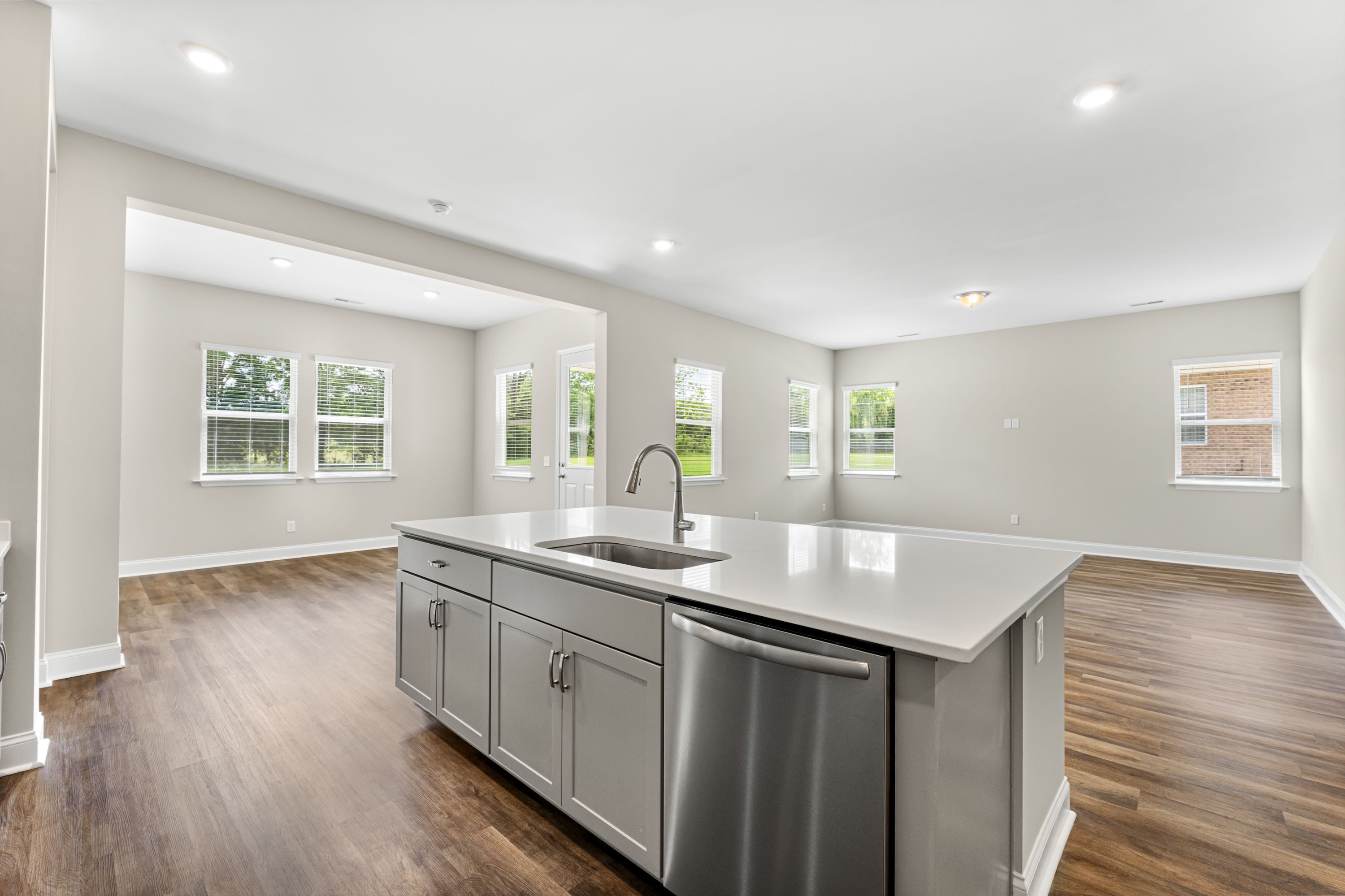 Modern kitchen in The Arcadia E featuring large quartz island, stainless steel sink, and open-concept layout