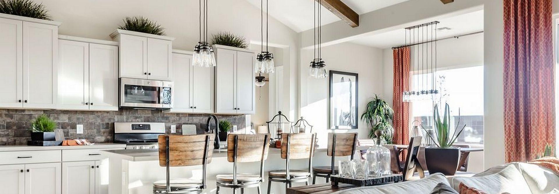 Open-concept kitchen and living room at Westwood in Prescott AZ with white cabinets, island bar stools, exposed beams, and cozy seating