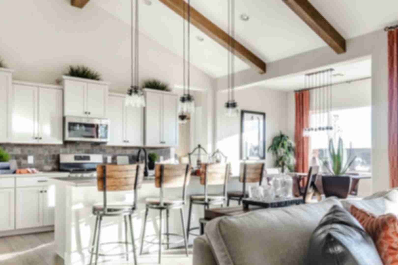 Open-concept kitchen and living room at Westwood in Prescott AZ with white cabinets, island bar stools, exposed beams, and cozy seating