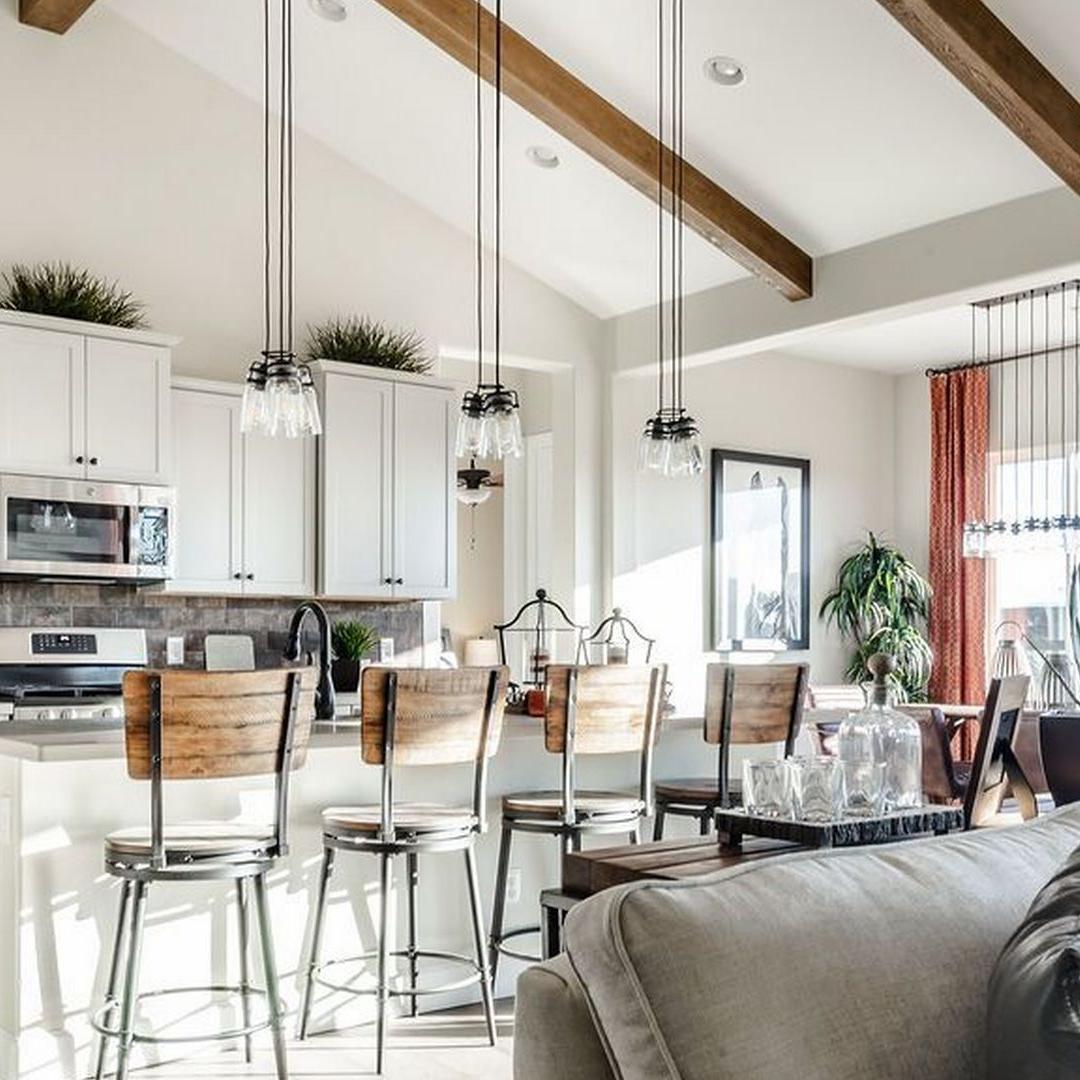 Open-concept kitchen and living room at Westwood in Prescott AZ with white cabinets, island bar stools, exposed beams, and cozy seating