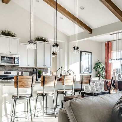 Open-concept kitchen and living room at Westwood in Prescott AZ with white cabinets, island bar stools, exposed beams, and cozy seating