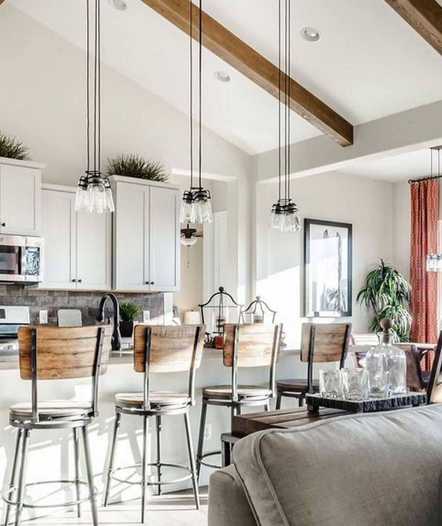 Open-concept kitchen and living room at Westwood in Prescott AZ with white cabinets, island bar stools, exposed beams, and cozy seating