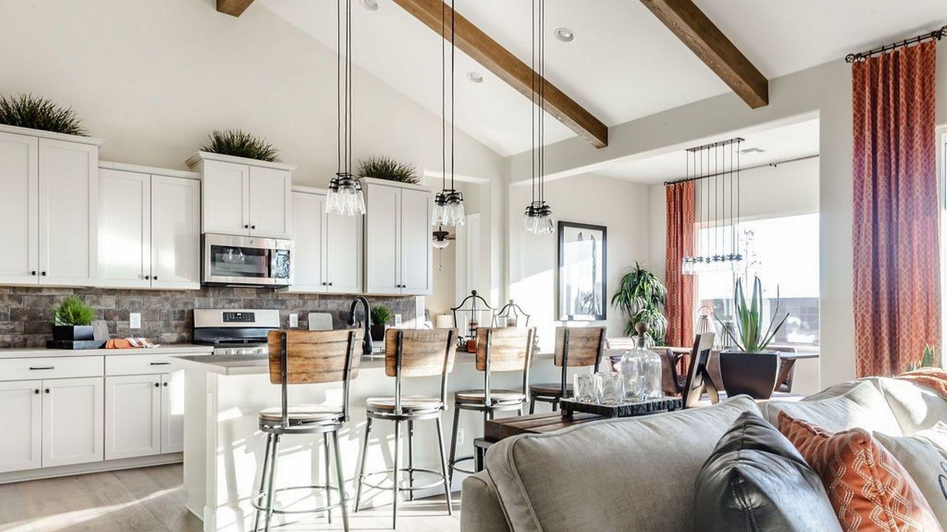 Open-concept kitchen and living room at Westwood in Prescott AZ with white cabinets, island bar stools, exposed beams, and cozy seating