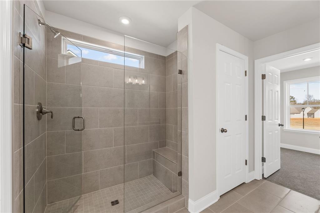 Modern frameless glass shower with gray tile, built-in bench, and clerestory window in Davidson Homes The Willow B master bath, Hoschton GA