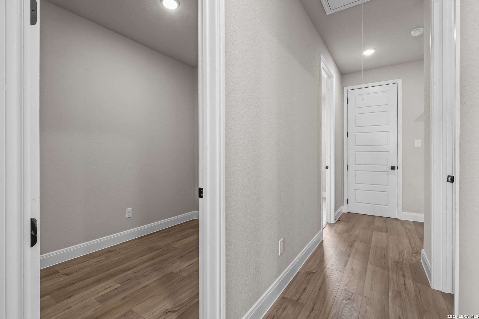 Hallway with wood-look flooring leading to bedrooms in Davidson Homes Foster E plan, Potranco Oaks, Castroville, Texas