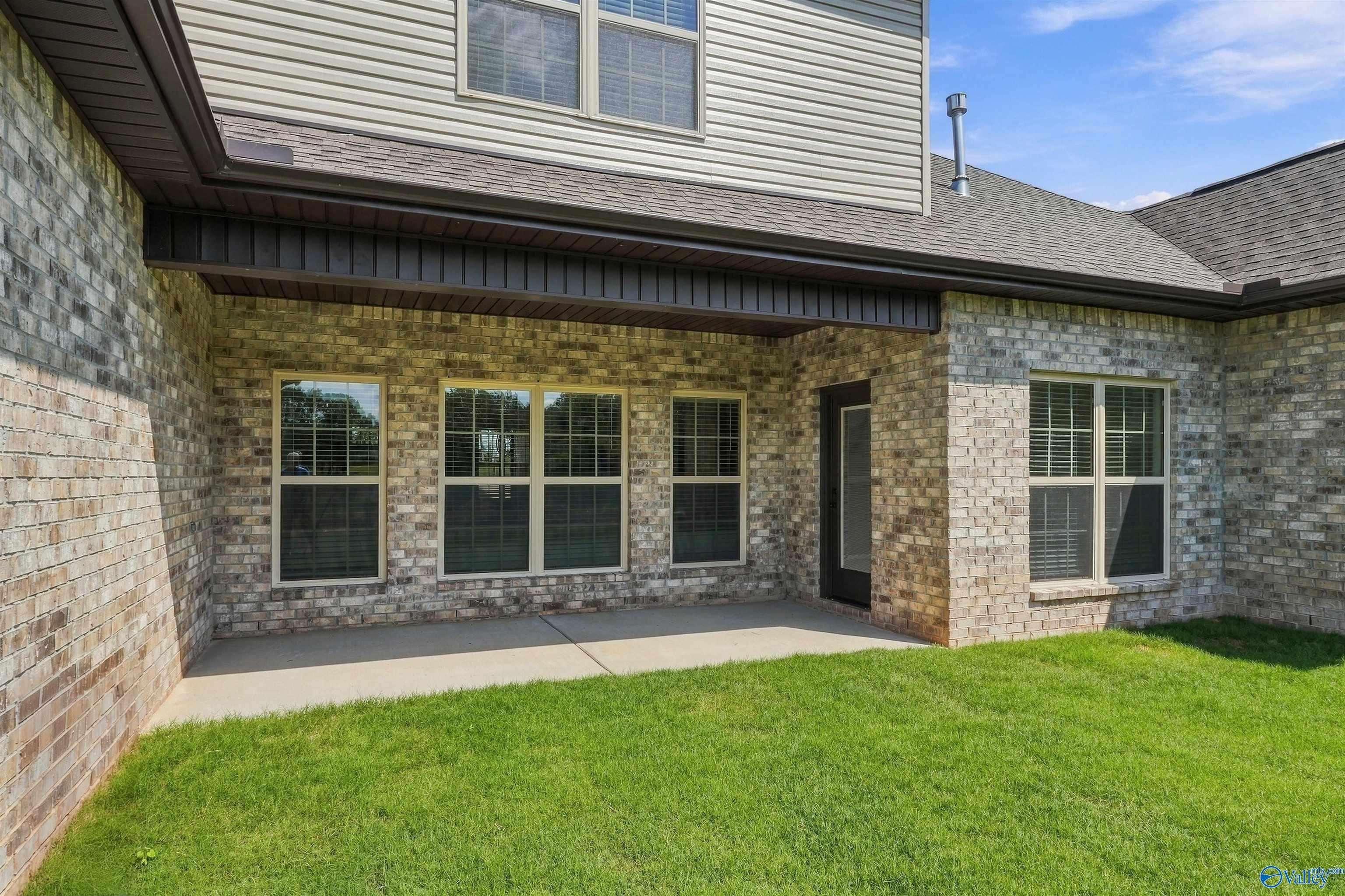 Covered concrete patio with brick exterior and large windows at Davidson Homes The Valencia in Riverton Preserve, Huntsville, Alabama