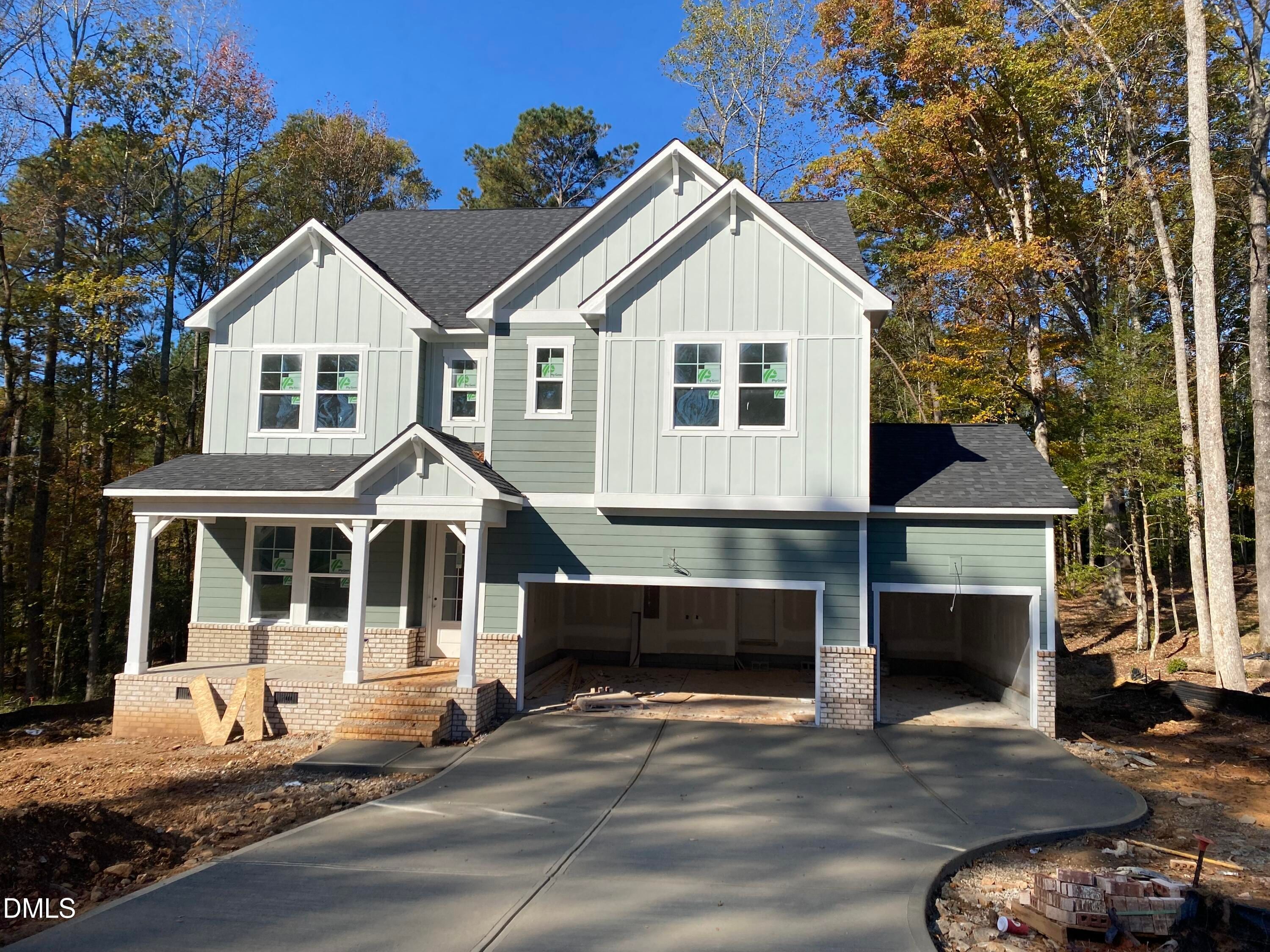 Modern 3-story sage green home with gabled roof, covered porch, 3-car garage, and autumn trees in Laneridge Estates, Raleigh, NC - The Beech B by Davidson Homes