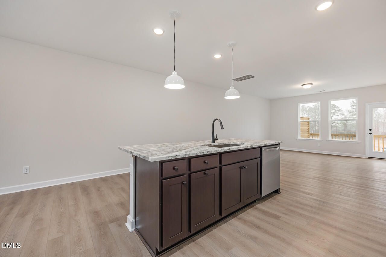 Modern kitchen island with quartz countertop, espresso cabinets, stainless dishwasher in Davidson Homes The Mitchell, Knightdale, NC